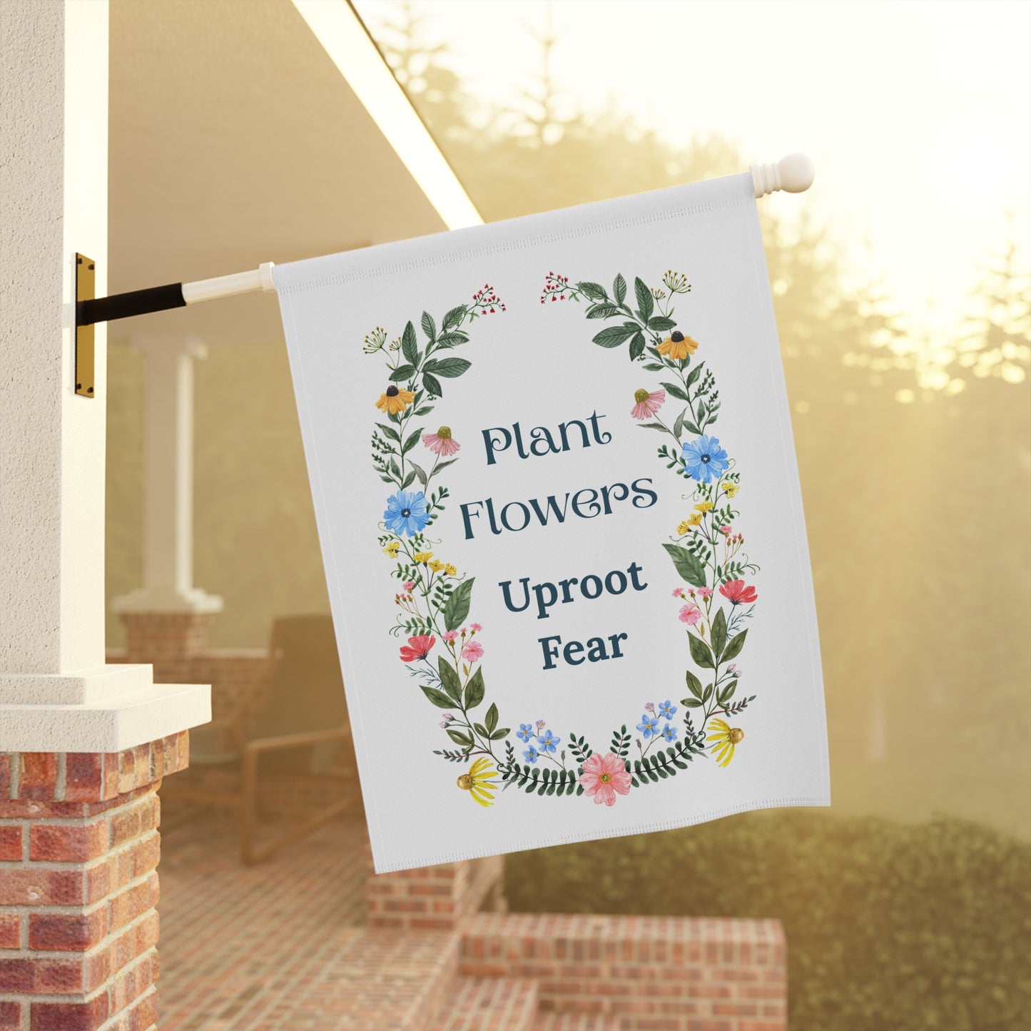 Decorative garden flag with floral design and motivational quote on a porch.