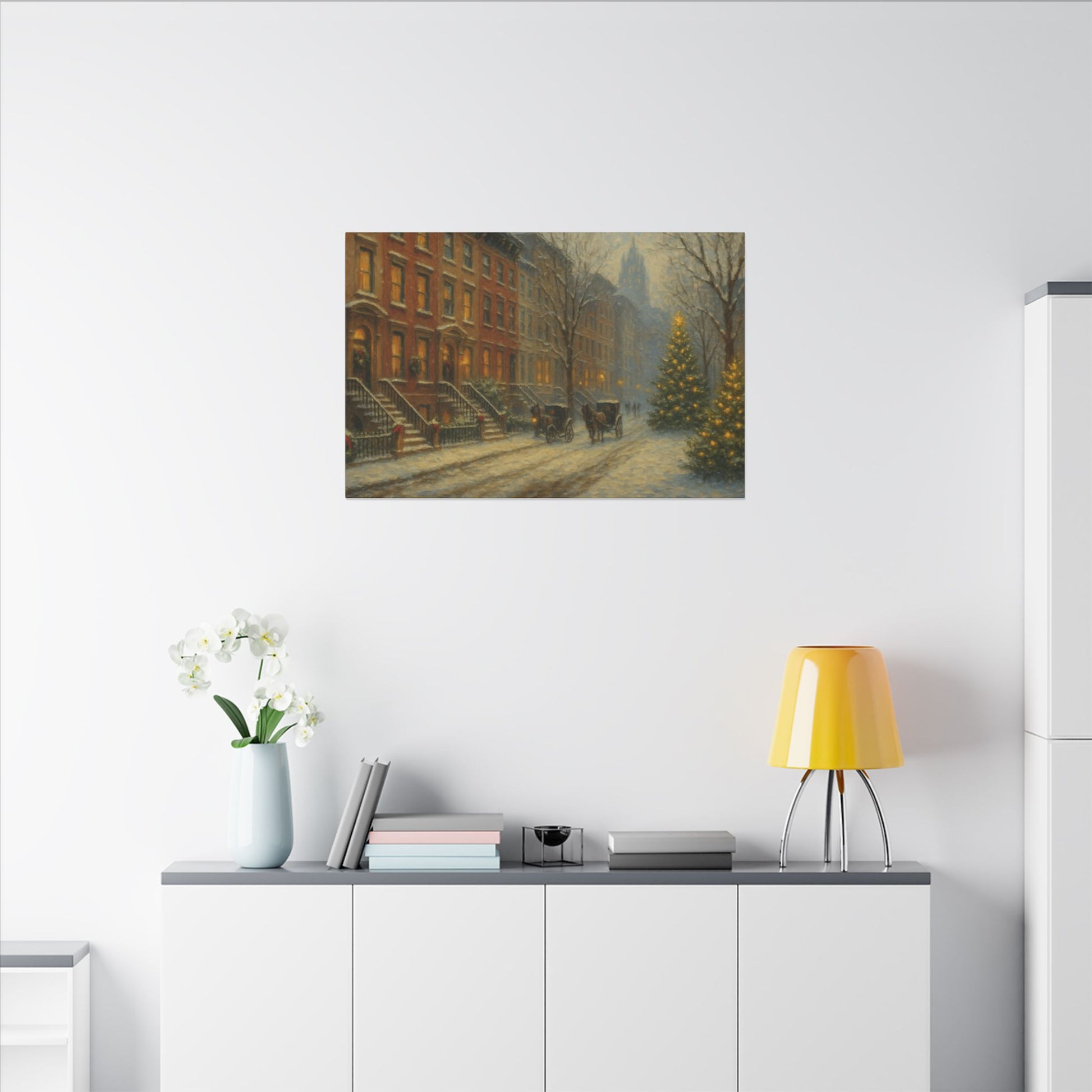 Framed artwork of a snowy street scene on a white wall above a shelf with decorative items.