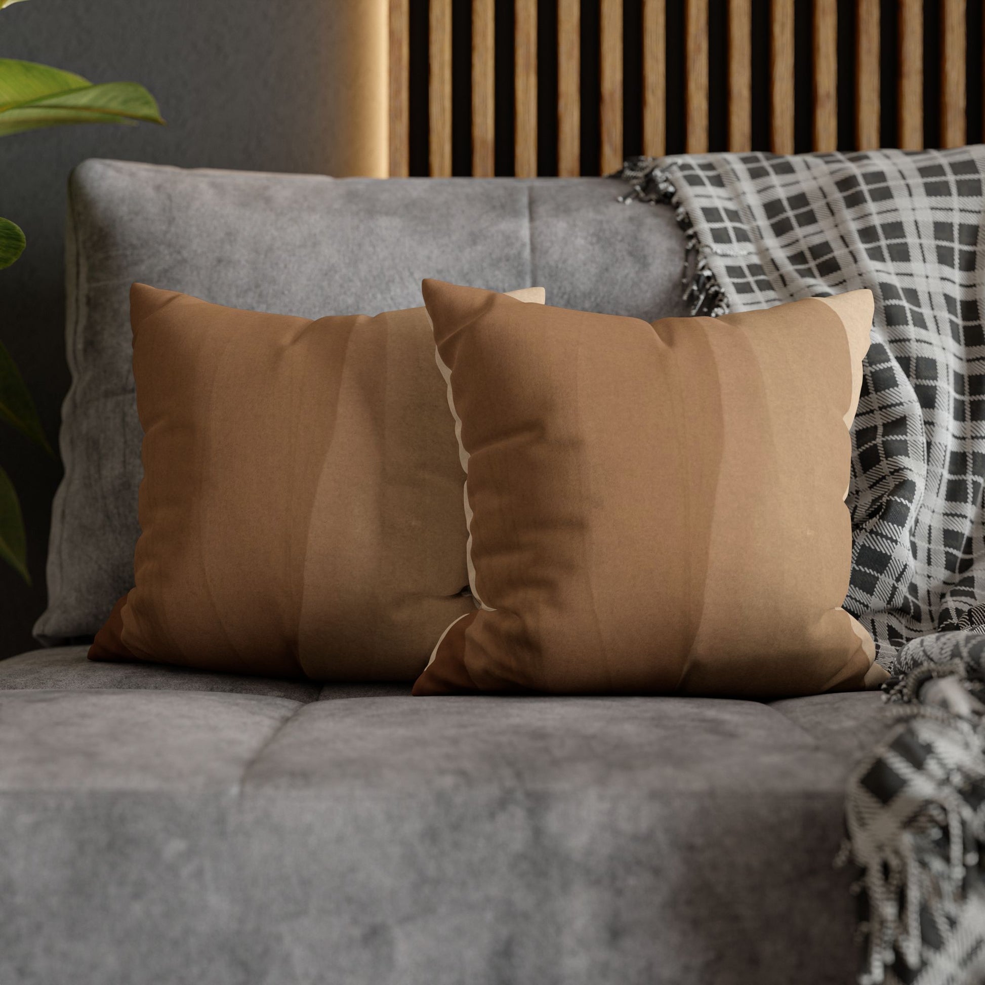 Brown pillows on a gray sofa with a plaid blanket