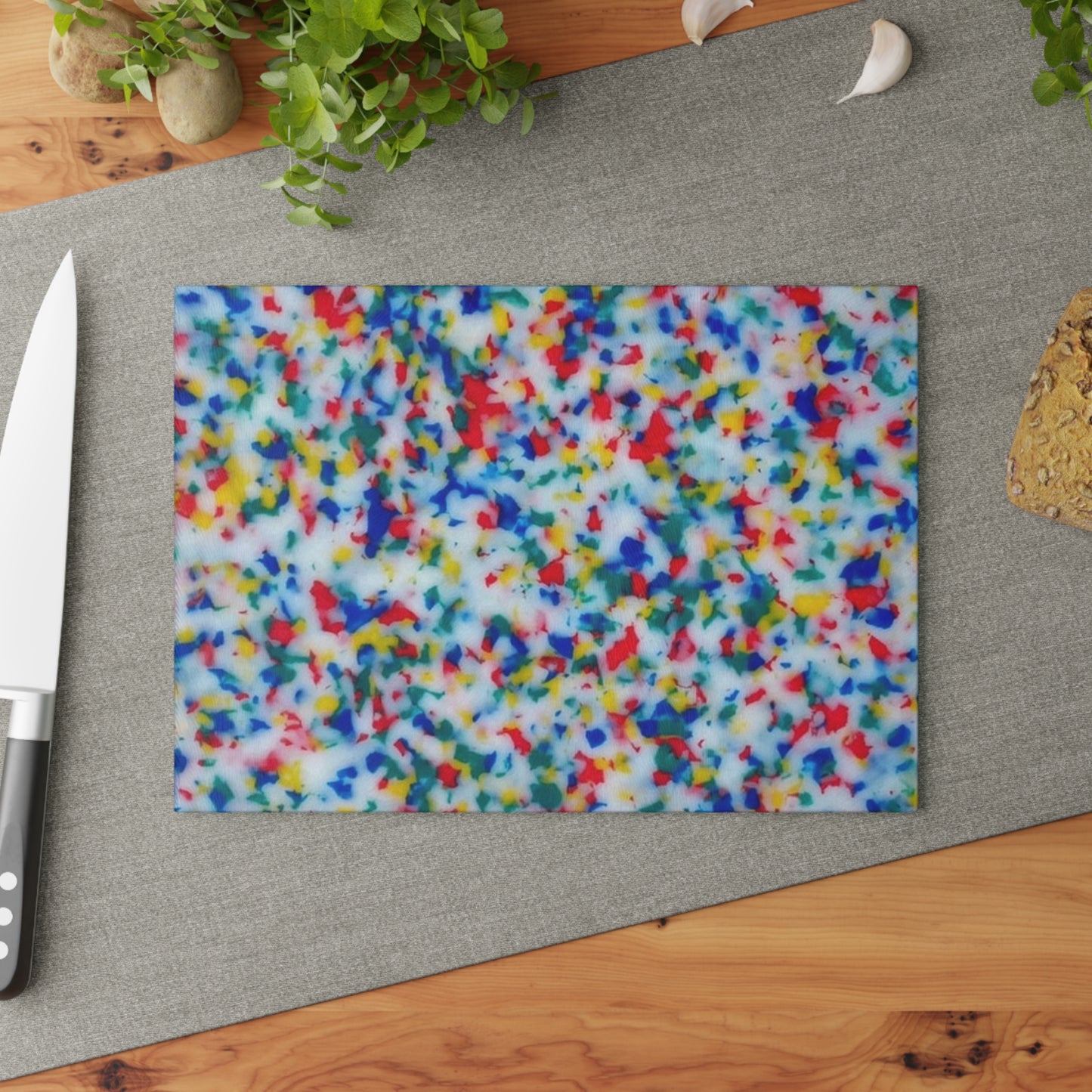 Colorful patterned cutting board on a kitchen surface with a knife and plant.