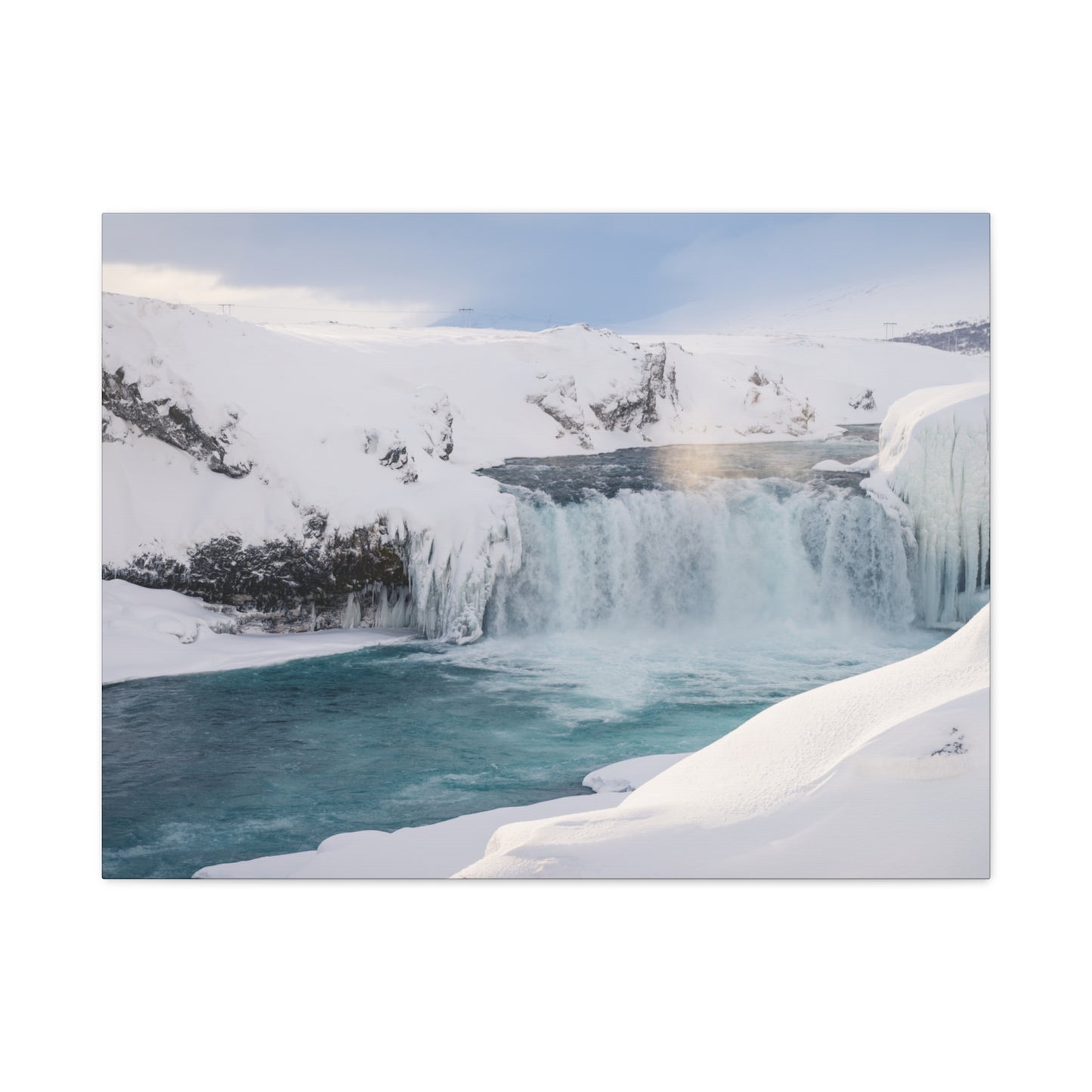 Frozen waterfall in a snowy landscape with a rainbow in the mist.