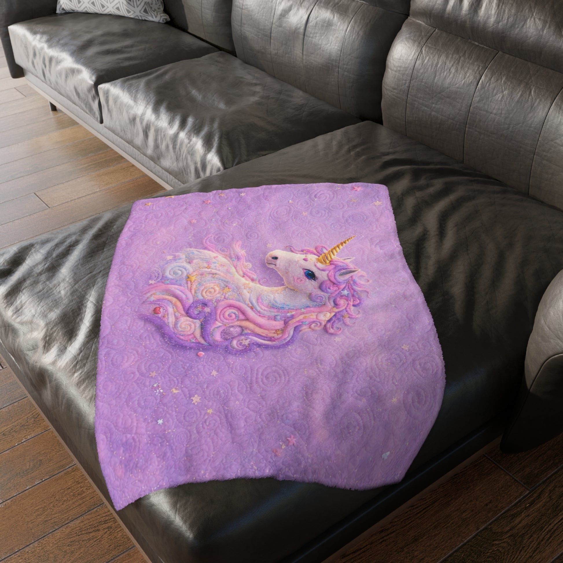 Purple blanket with a unicorn design on a black leather sofa.