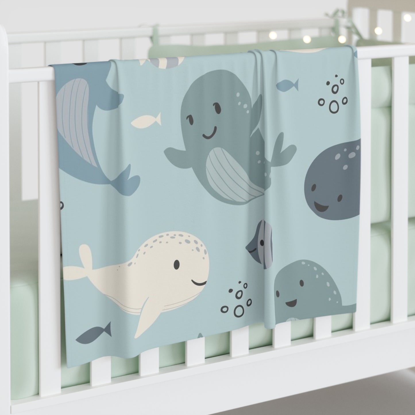 Baby crib with a blue blanket featuring whale illustrations
