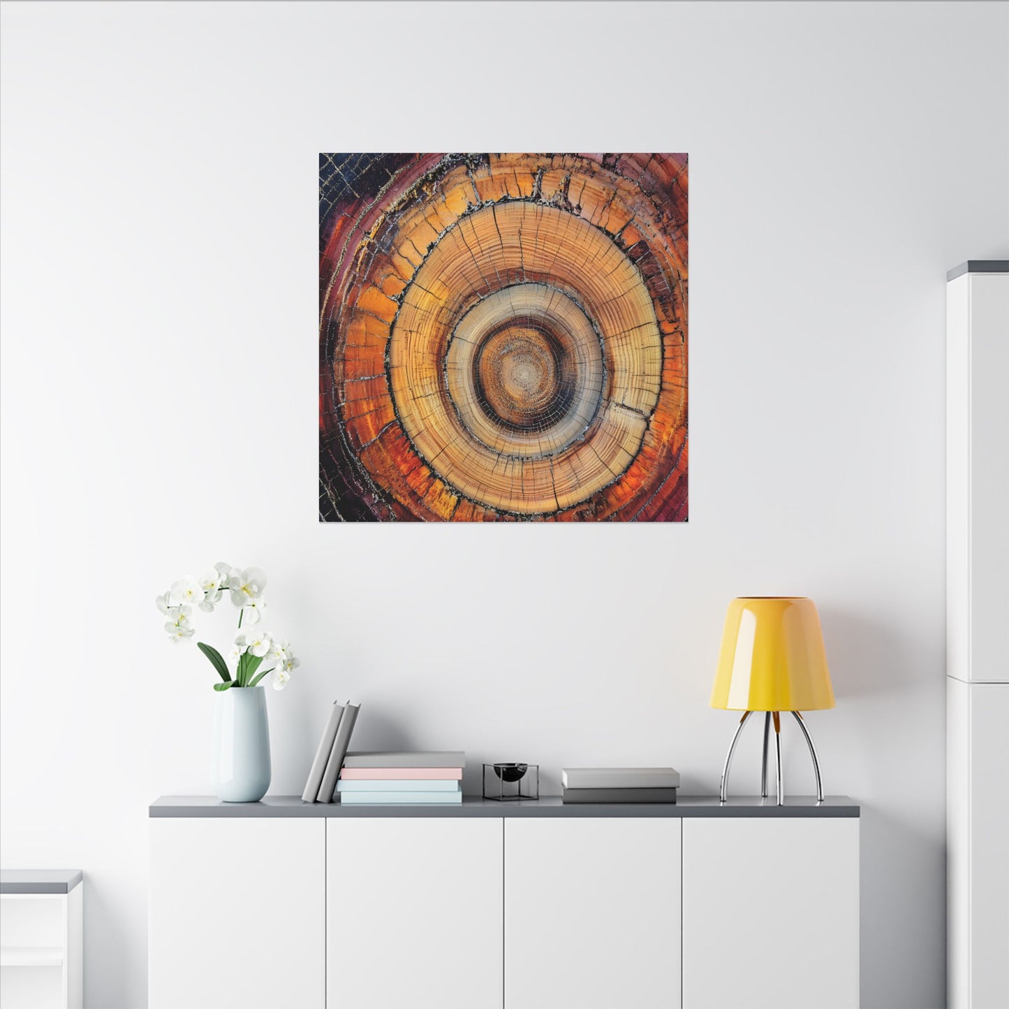 Wooden wall art piece on a white wall above a cabinet with a yellow lamp and white flowers.