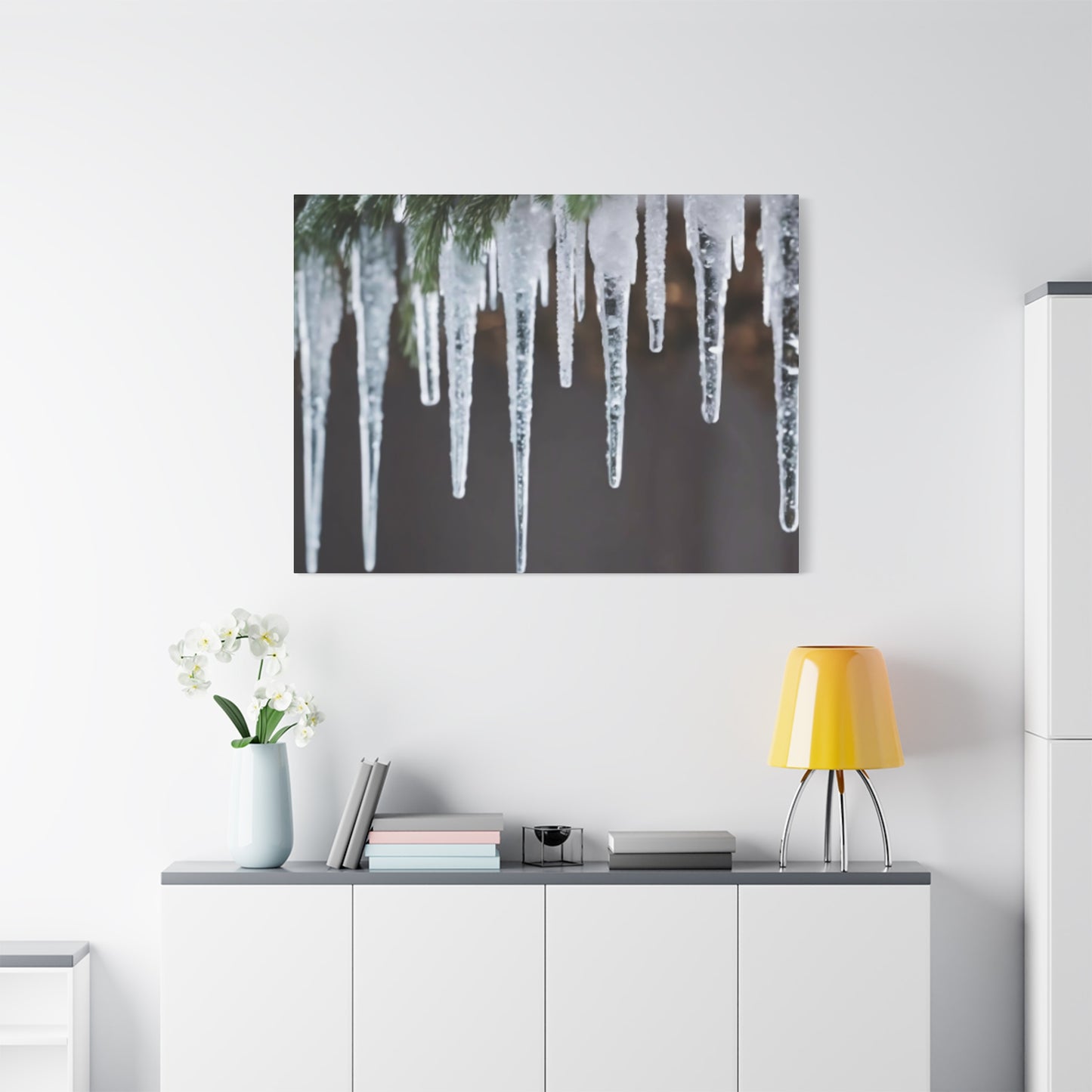 Canvas print of icicles hanging from a branch on a white wall above a desk.
