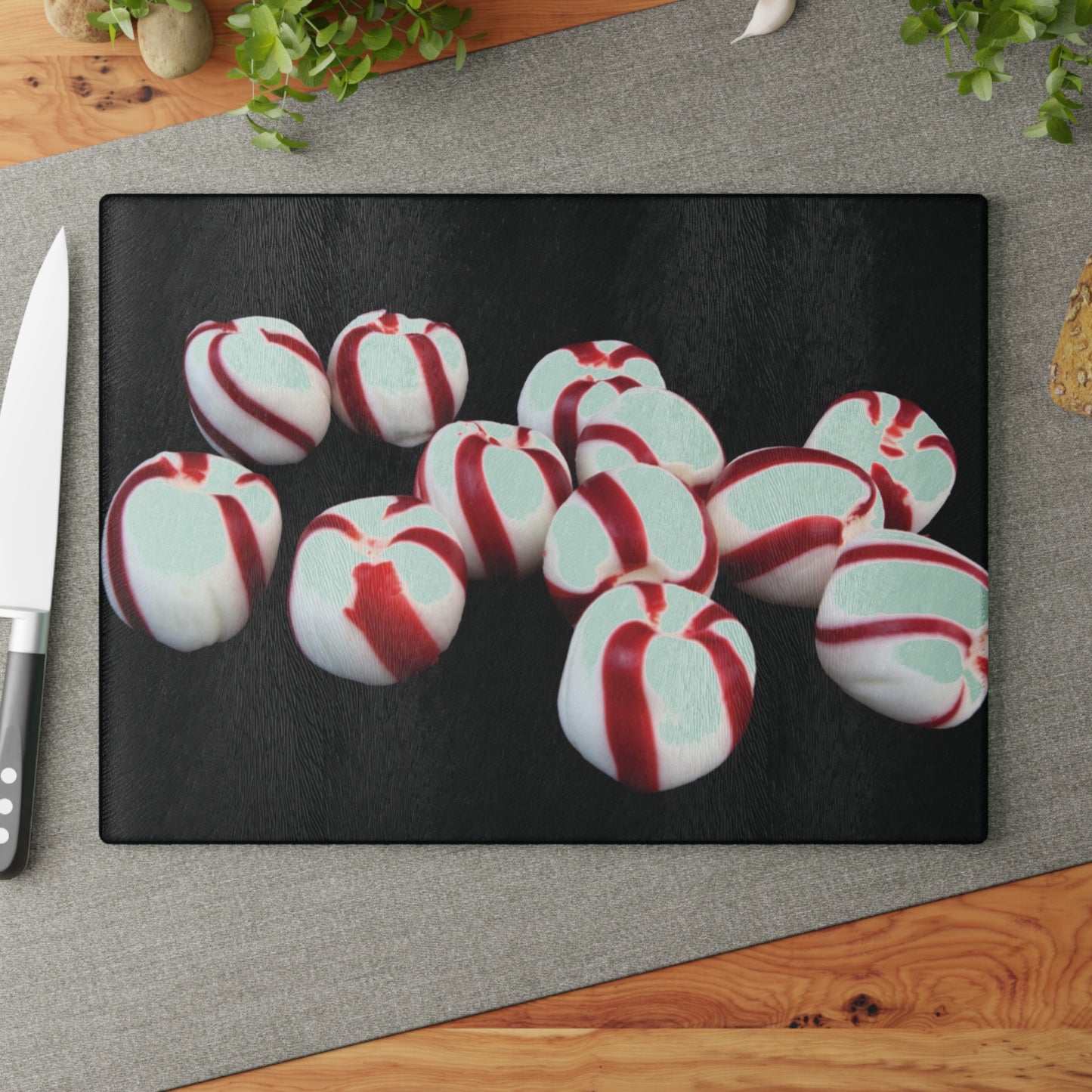 Peppermint candies on a black cutting board with a knife beside it on a gray surface.