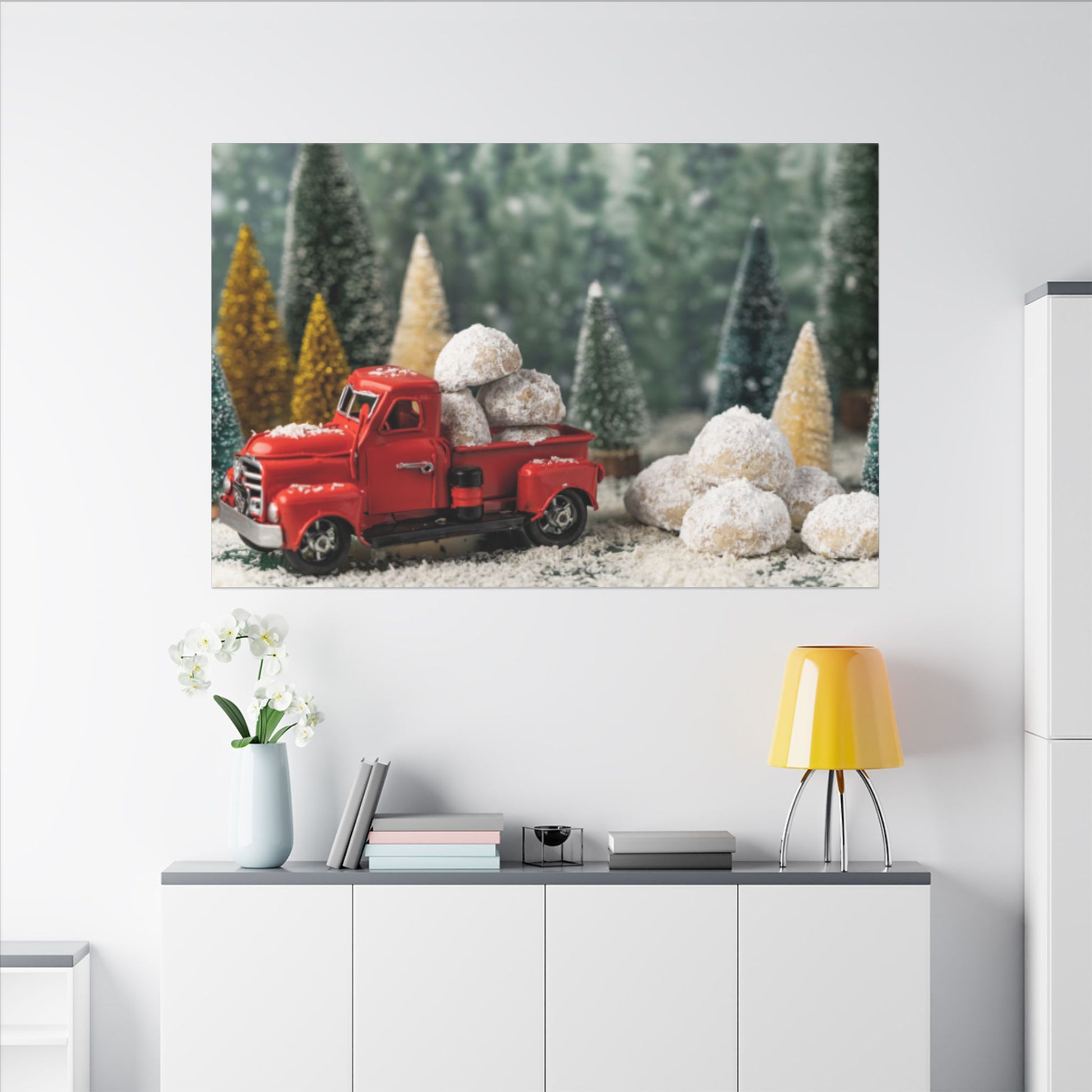 Red truck with Christmas trees and snowballs on a wall poster above a white cabinet.