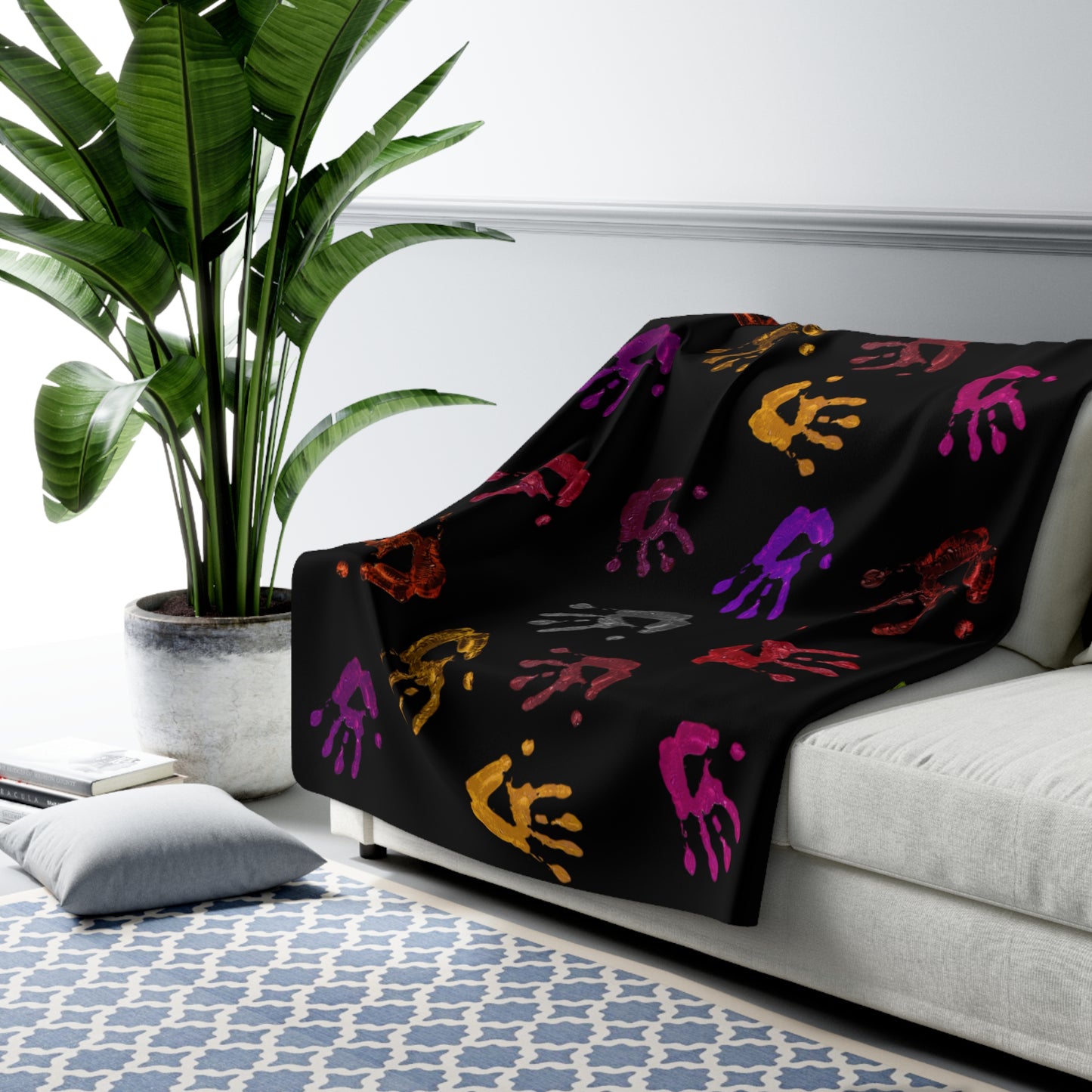 Black blanket with colorful patterns draped over a white couch in a living room setting.