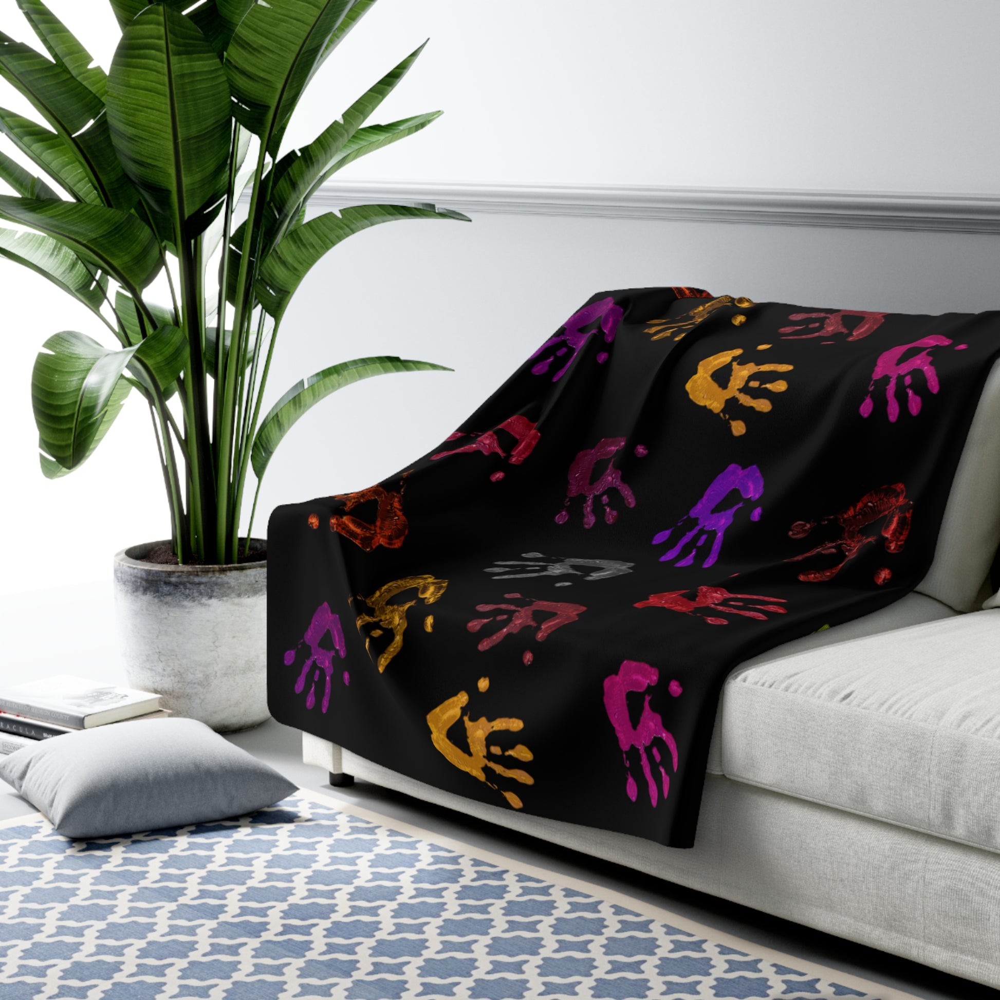 Black blanket with colorful patterns draped over a white couch in a living room setting.