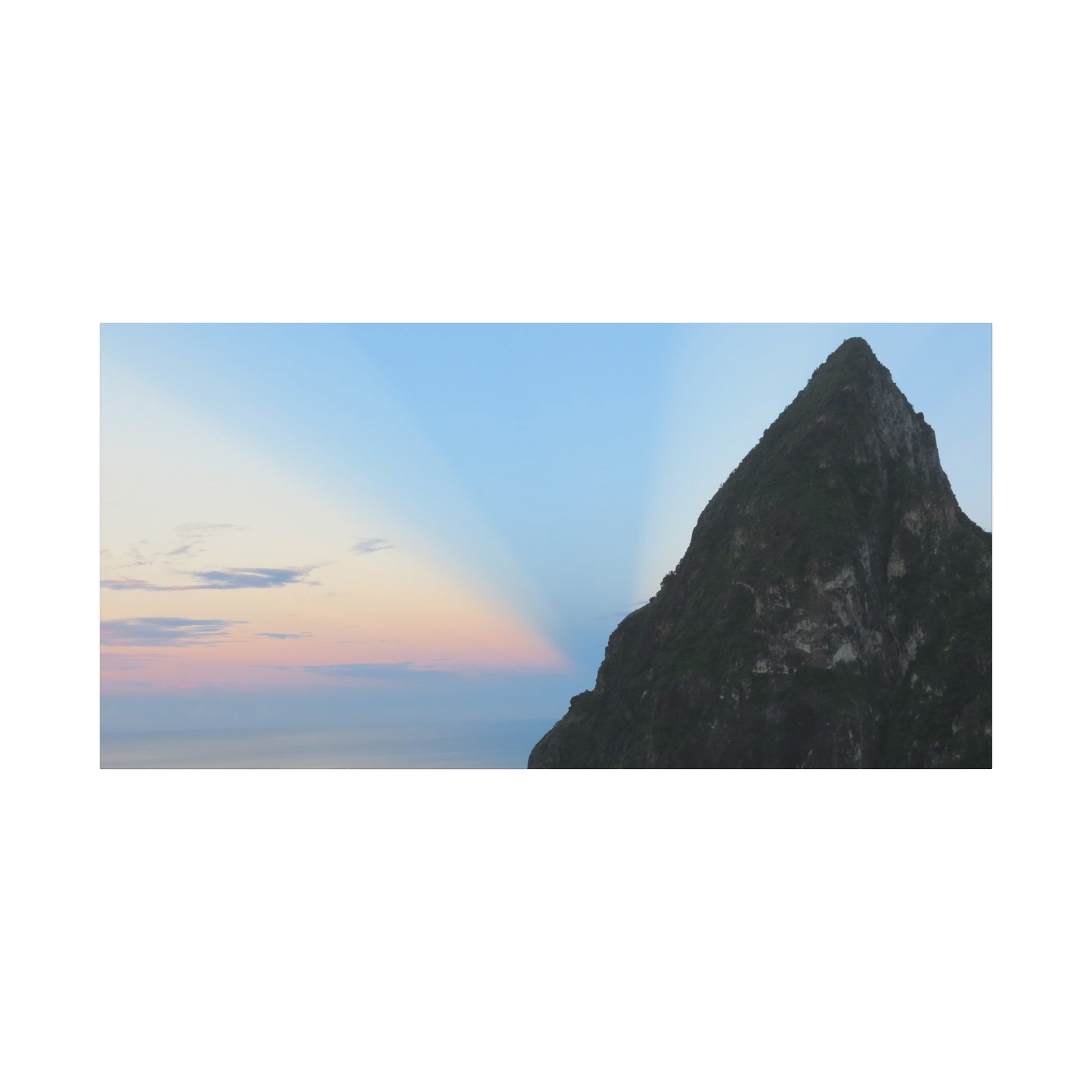 Tall, dark rock formation against a blue sky with a colorful cloud.