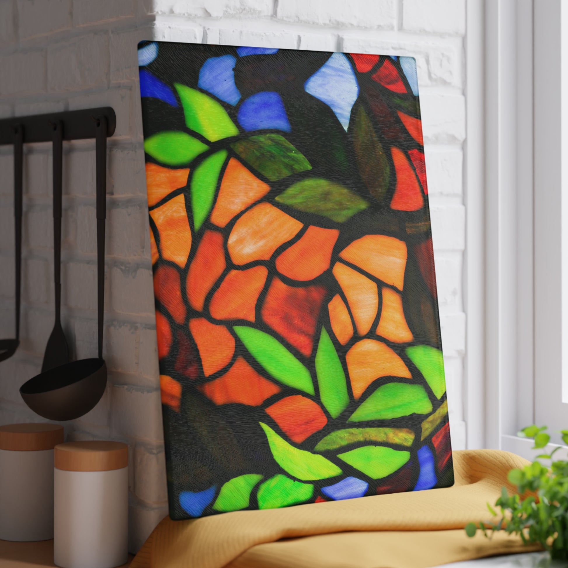 Colorful stained glass-style artwork on a kitchen counter with utensils and a plant.
