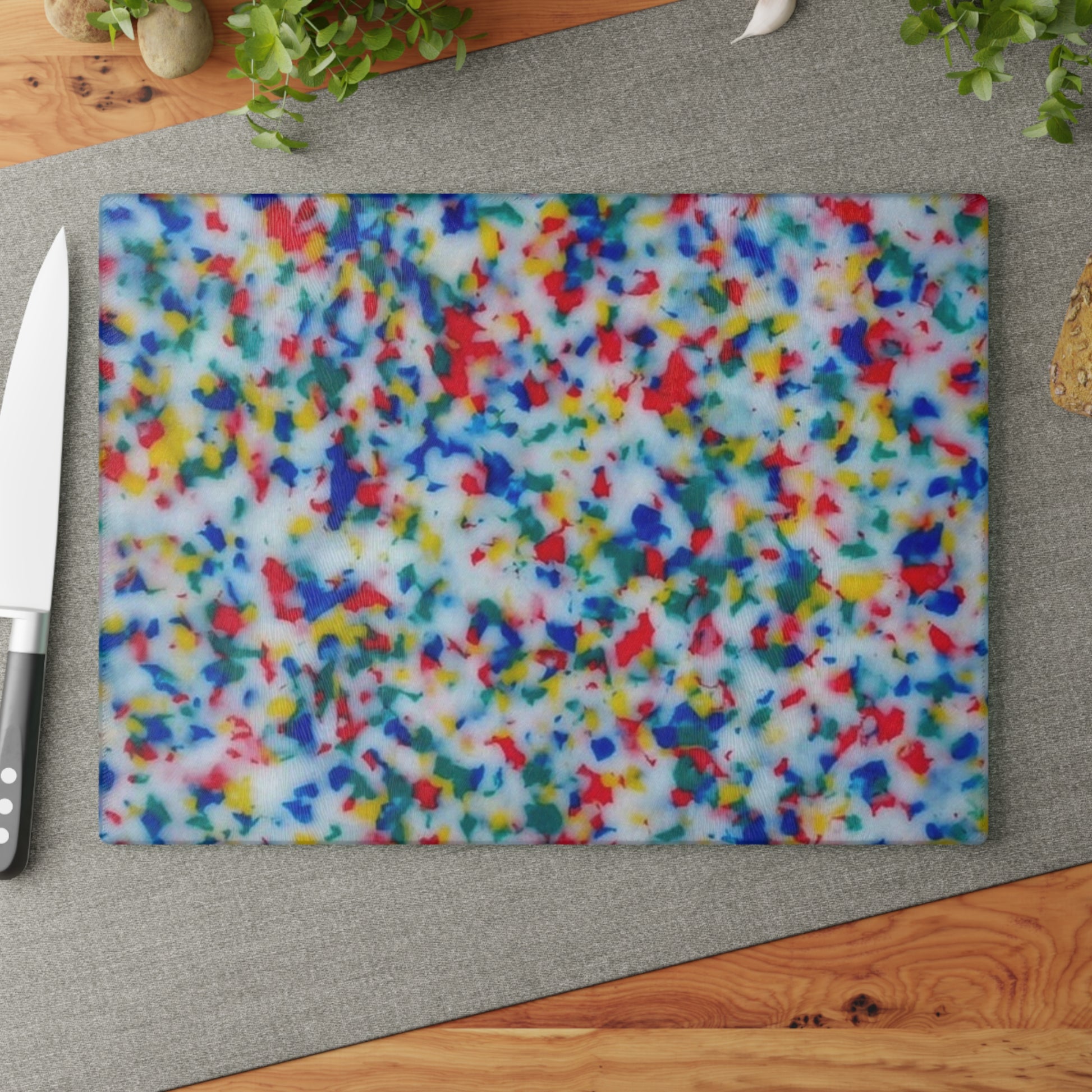 Colorful speckled cutting board on a wooden surface with a knife.
