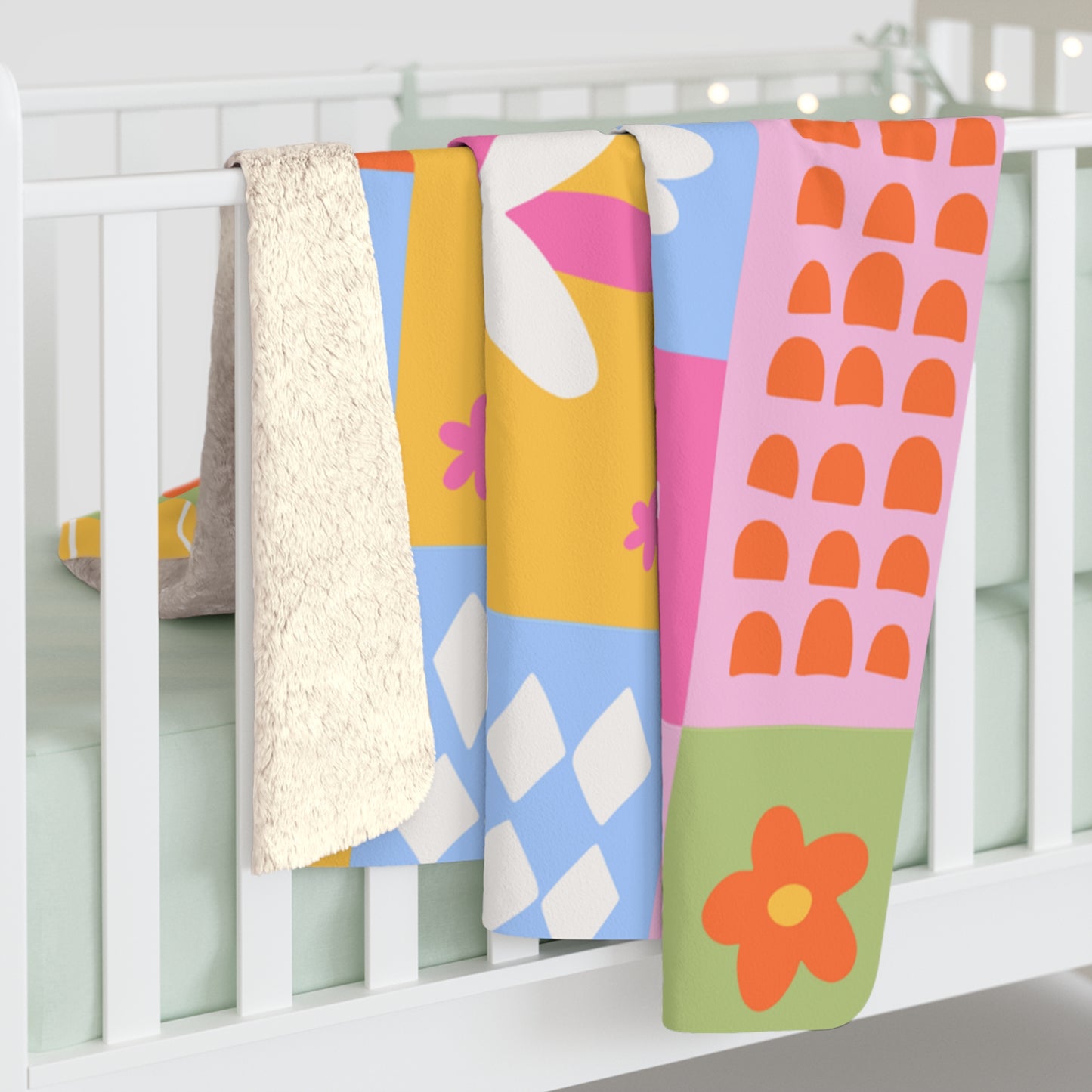 Colorful baby blankets with patterns hanging on a white crib