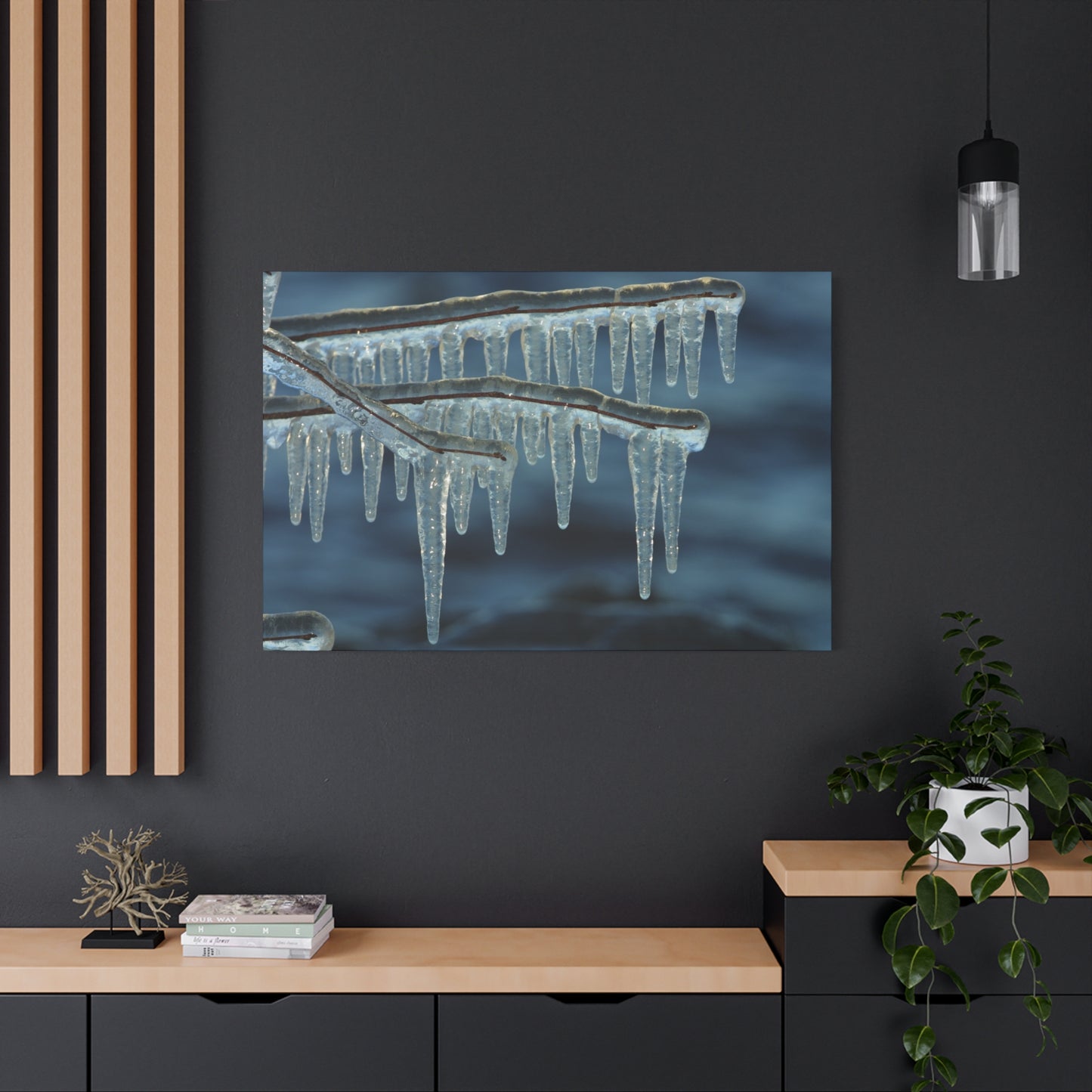 Framed artwork of icicles on a dark wall with a wooden shelf and plant.