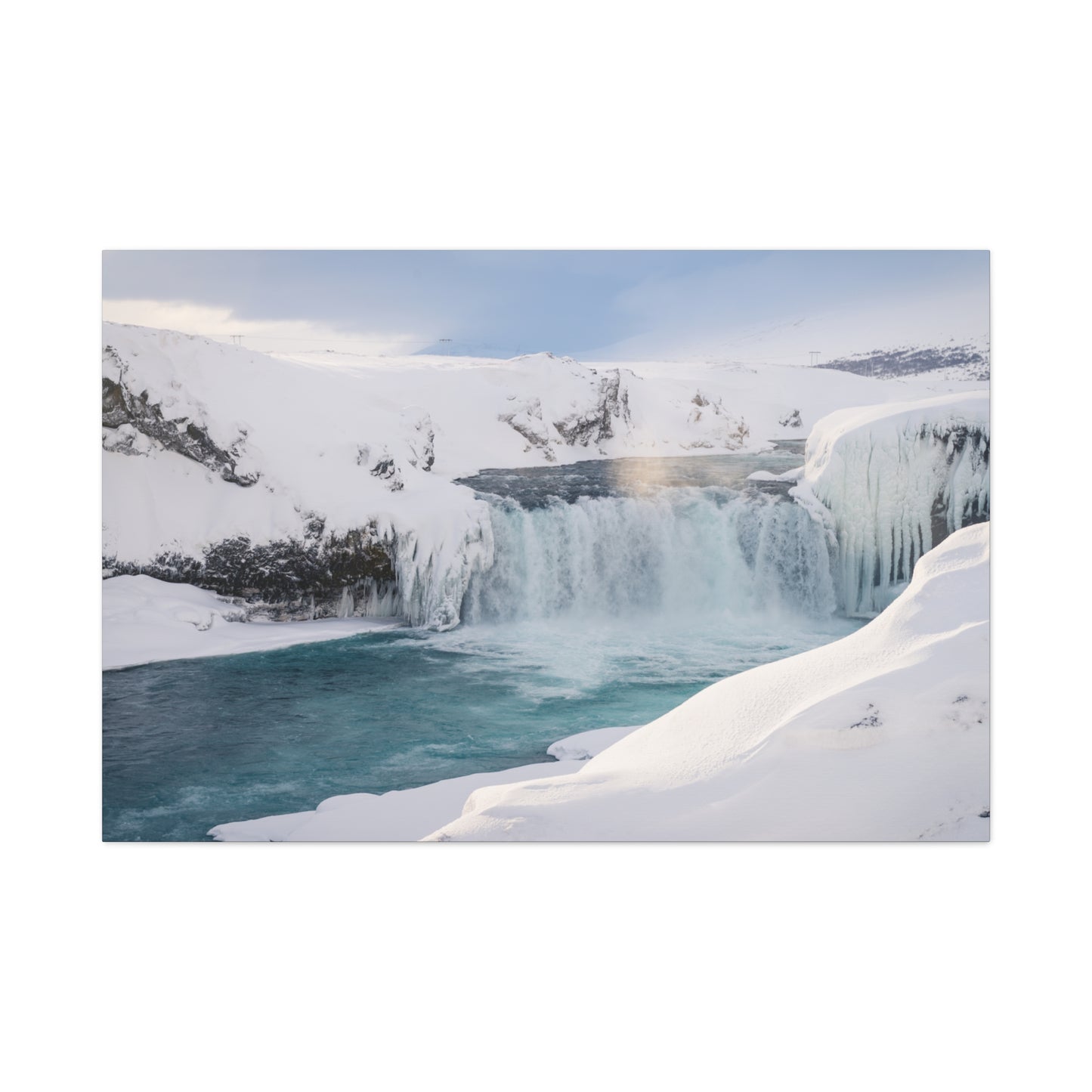 Frozen waterfall in a snowy landscape with ice formations.