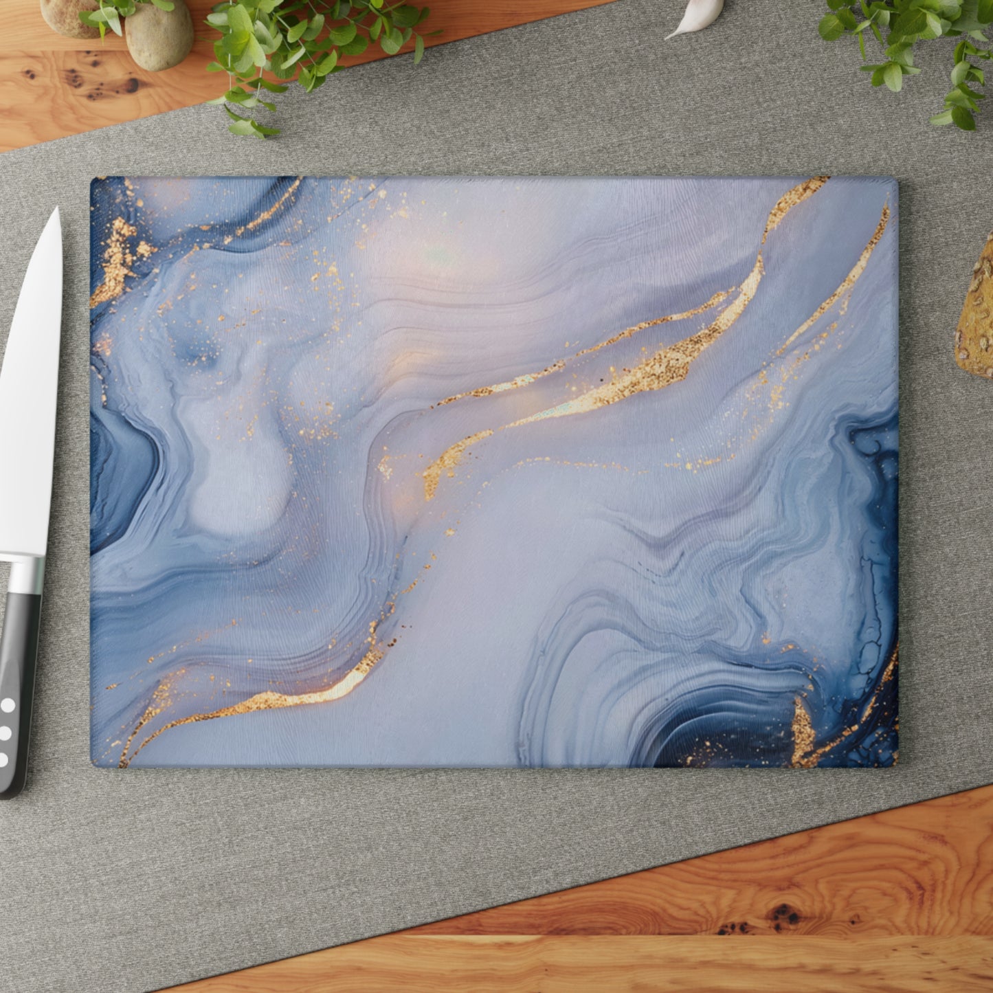 Blue marbled cutting board with gold accents on a gray surface with a knife.