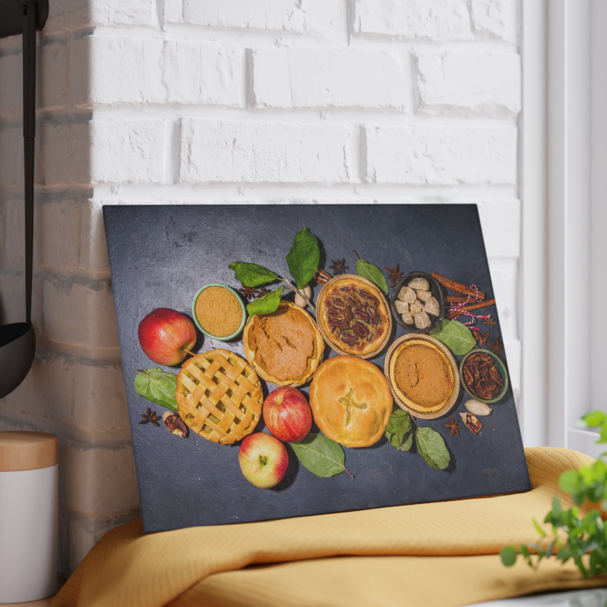 Decorative wall art with pies and apples on a dark background, leaning against a white brick wall.