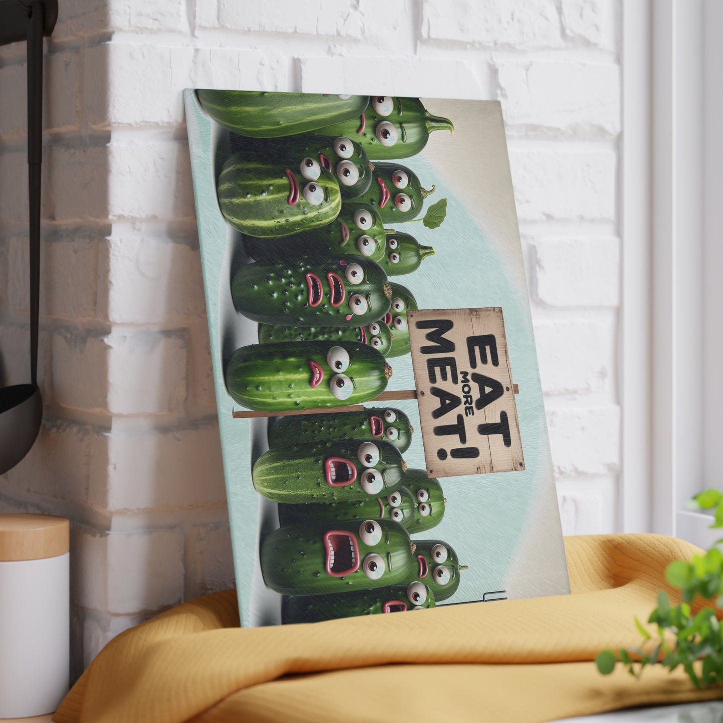 Canvas print with cartoon cucumbers and 'Eat More Meat' sign against a white brick wall.