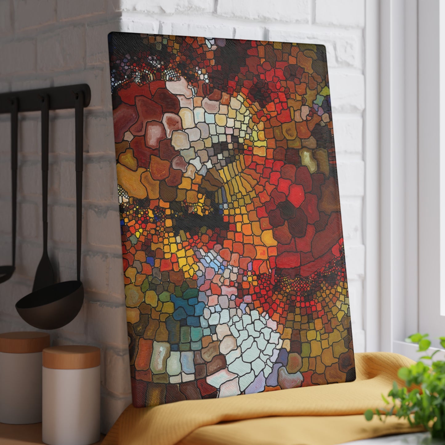 Colorful mosaic art piece on a kitchen wall with utensils and a plant.