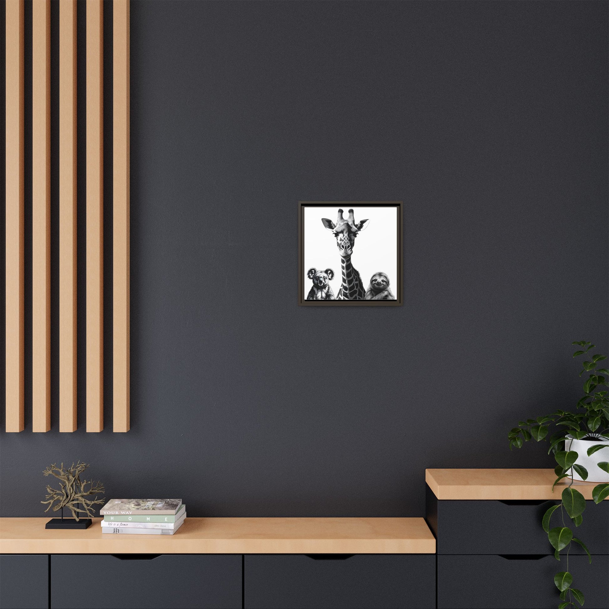 Framed artwork of a giraffe and two cubs on a dark gray wall above a wooden shelf.