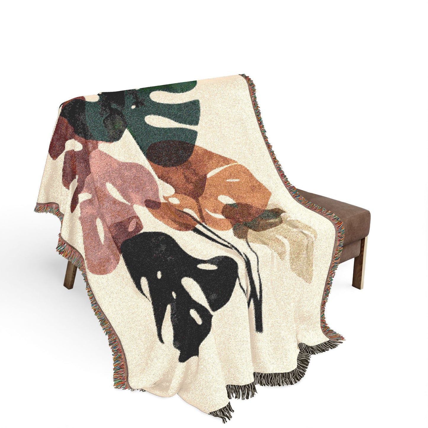 Decorative throw blanket with leaf pattern draped over a chair on a white background