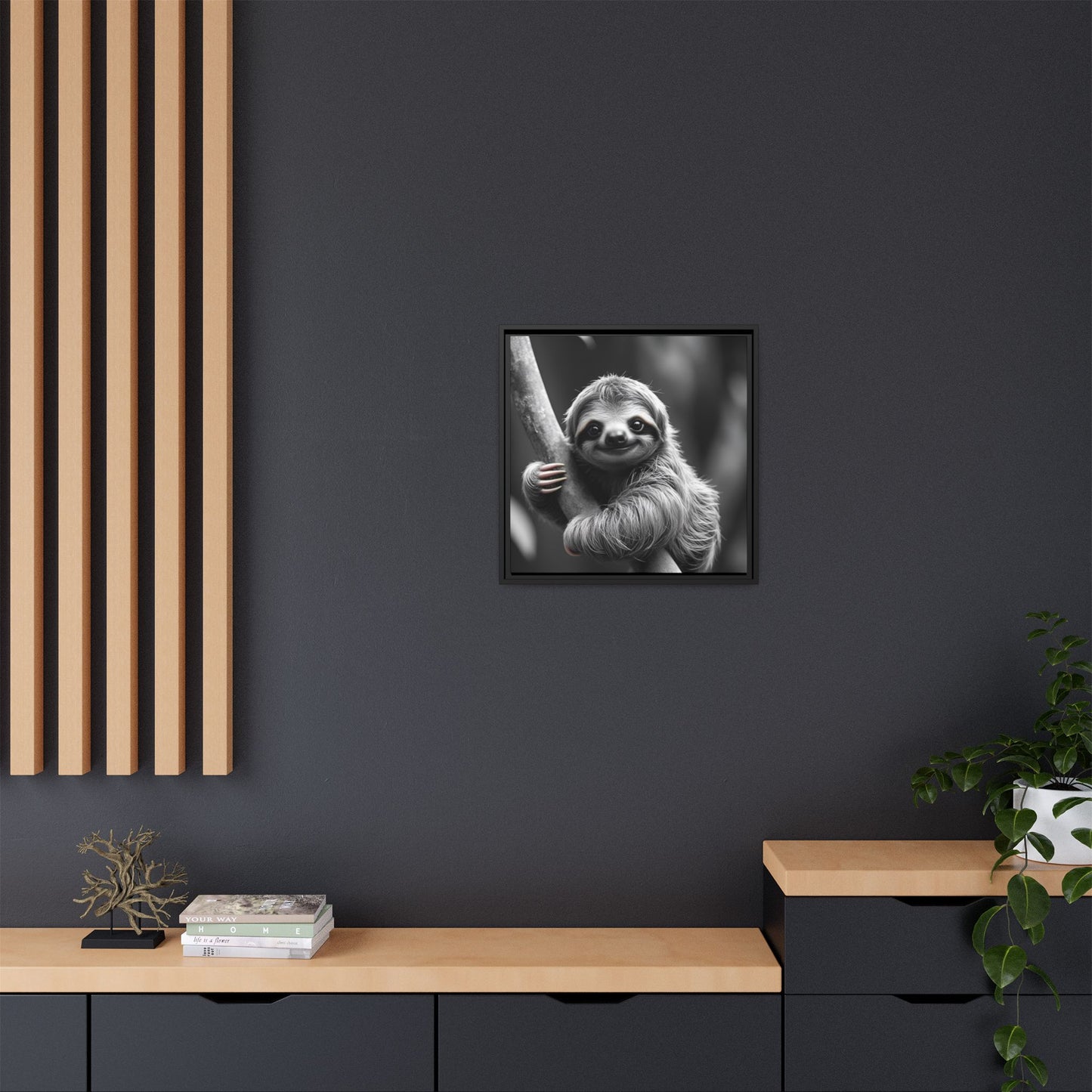 Framed black and white sloth print on a dark wall with wooden shelves and decor.