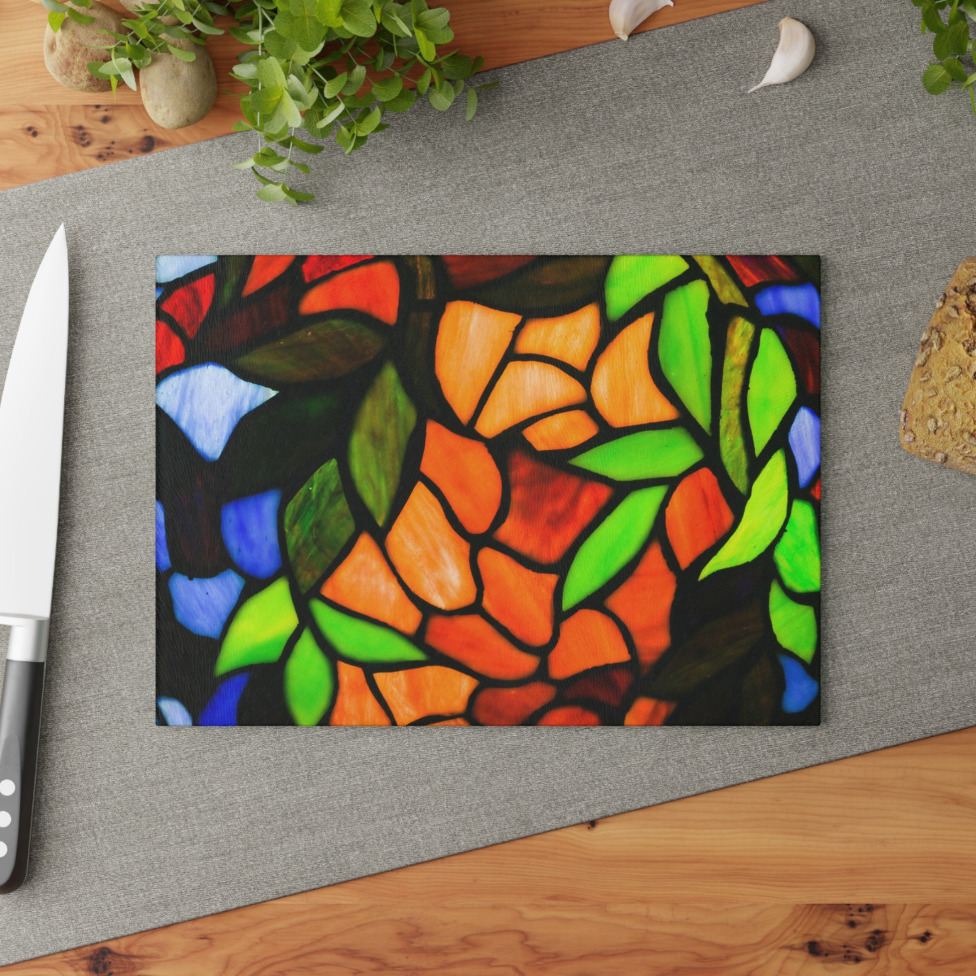 Colorful stained glass design on a cutting board with a knife and plant in the background.