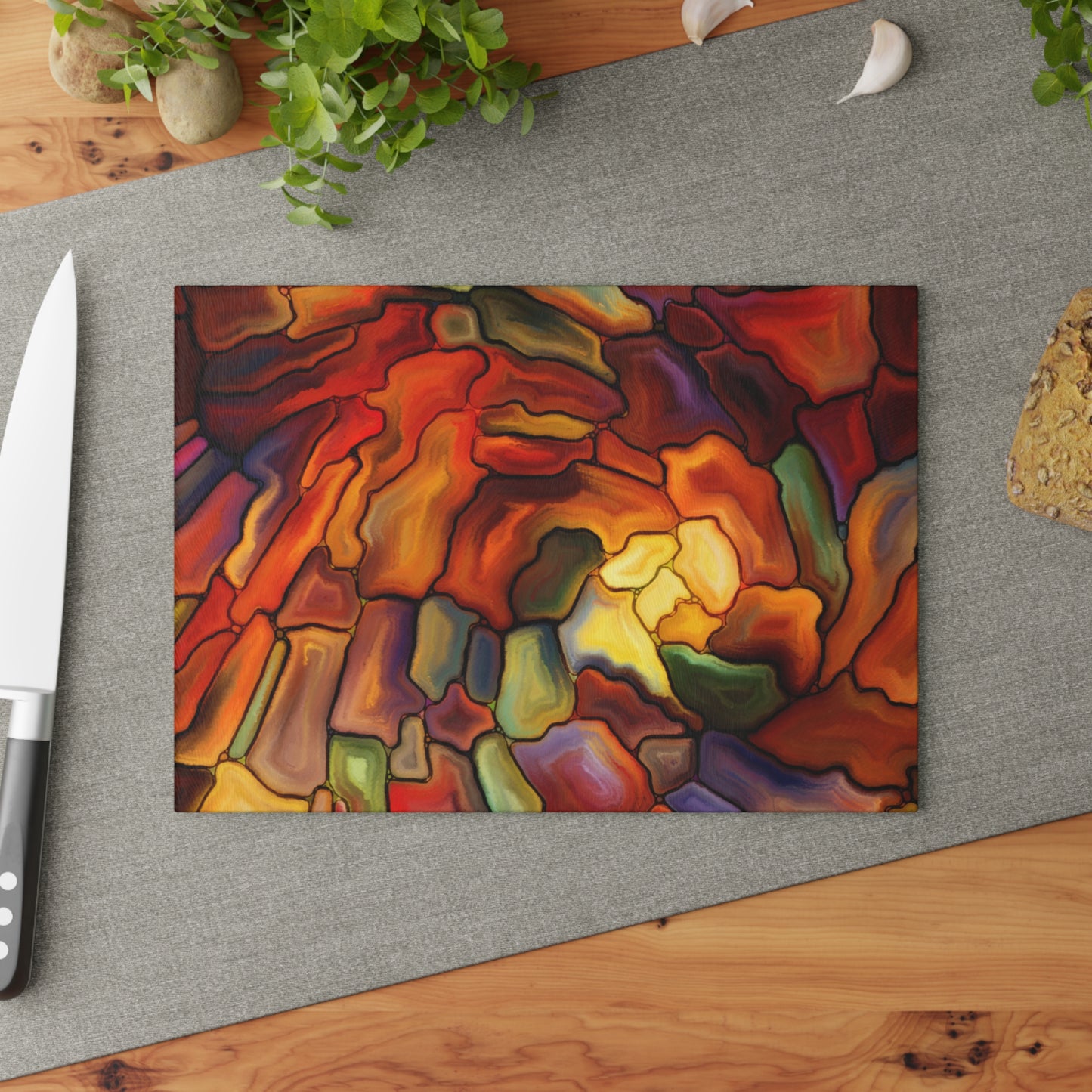 Colorful abstract painting on a gray surface with a knife and plant in the background