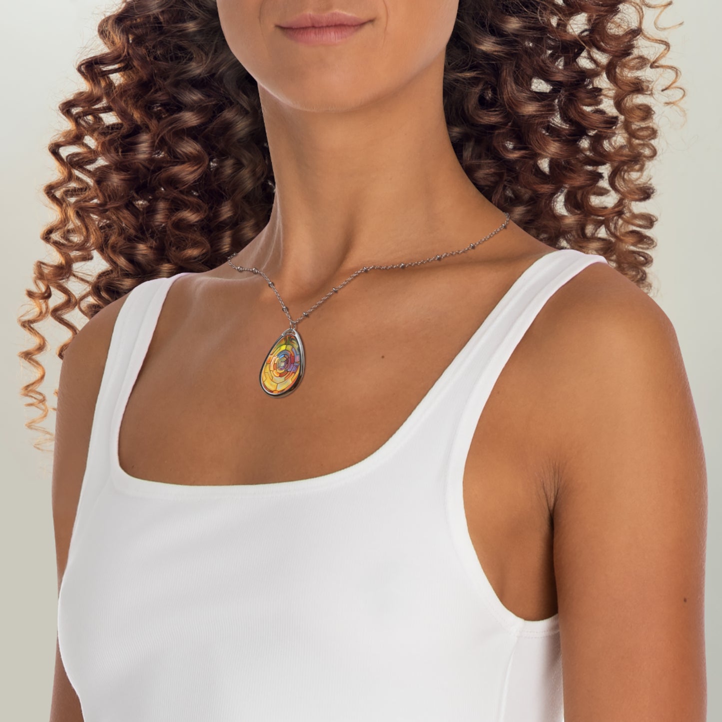 Woman wearing a white tank top with a necklace featuring a blue pendant.