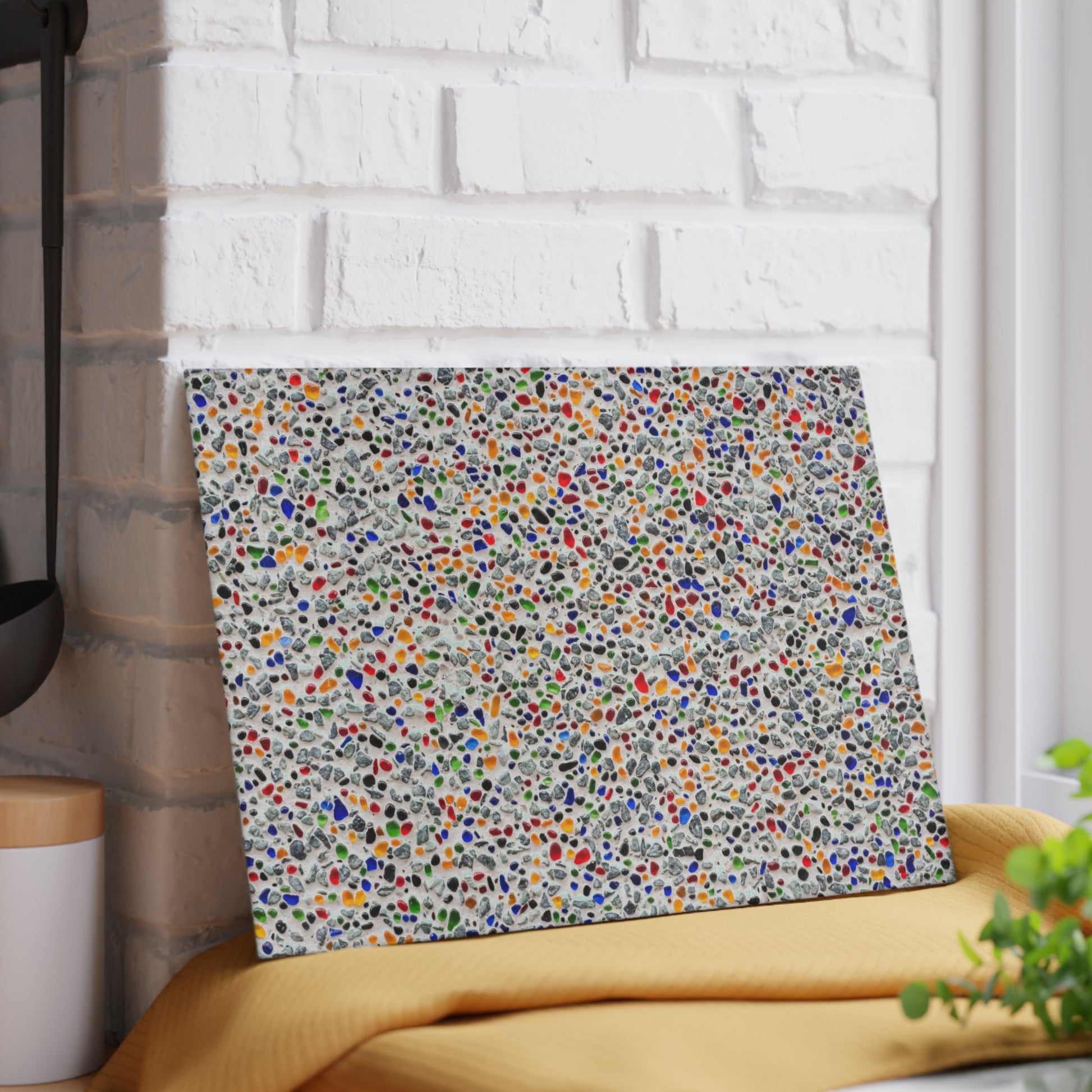 Colorful abstract patterned wall art leaning against a white brick wall.