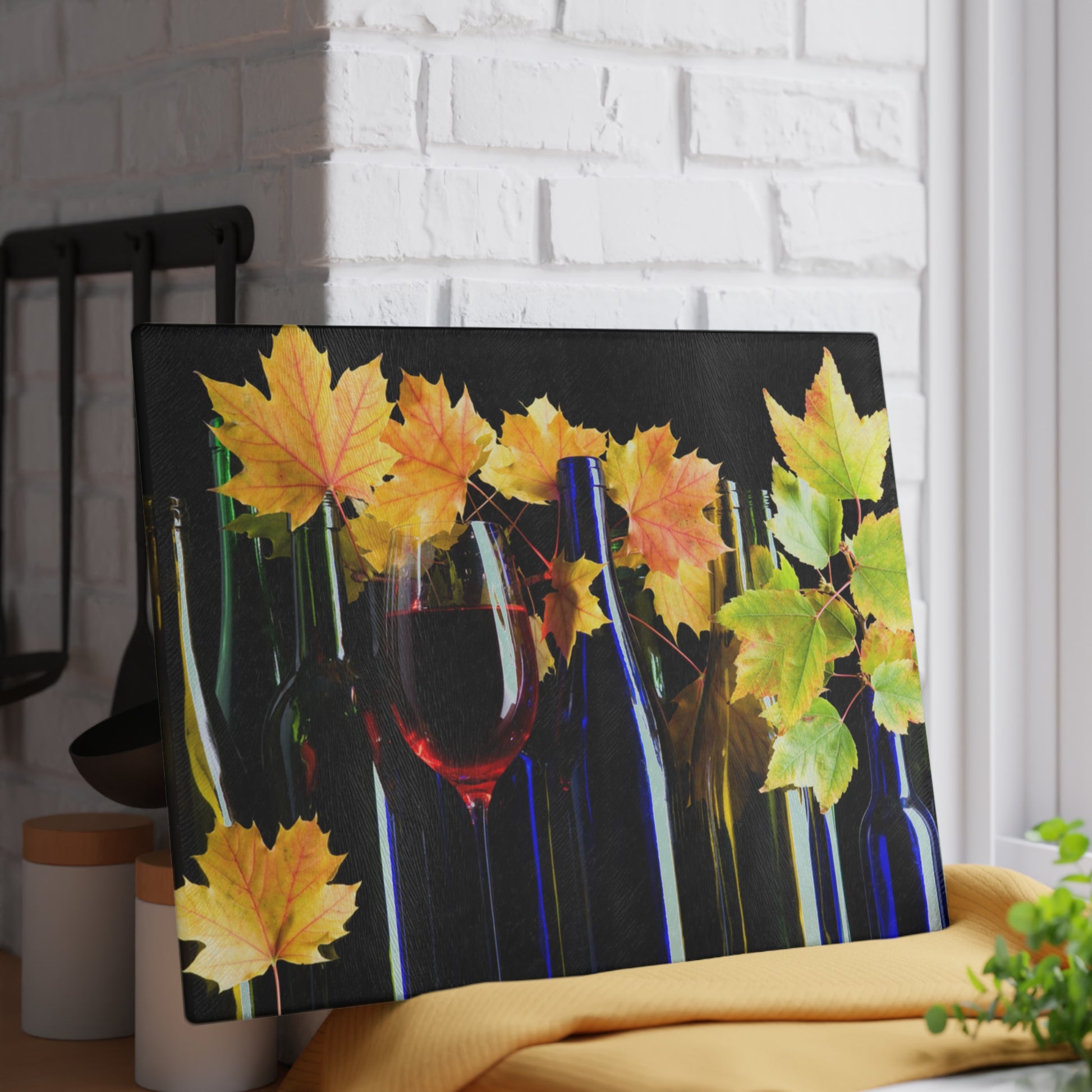 Decorative wall art with wine bottles, a glass, and autumn leaves on a black background.
