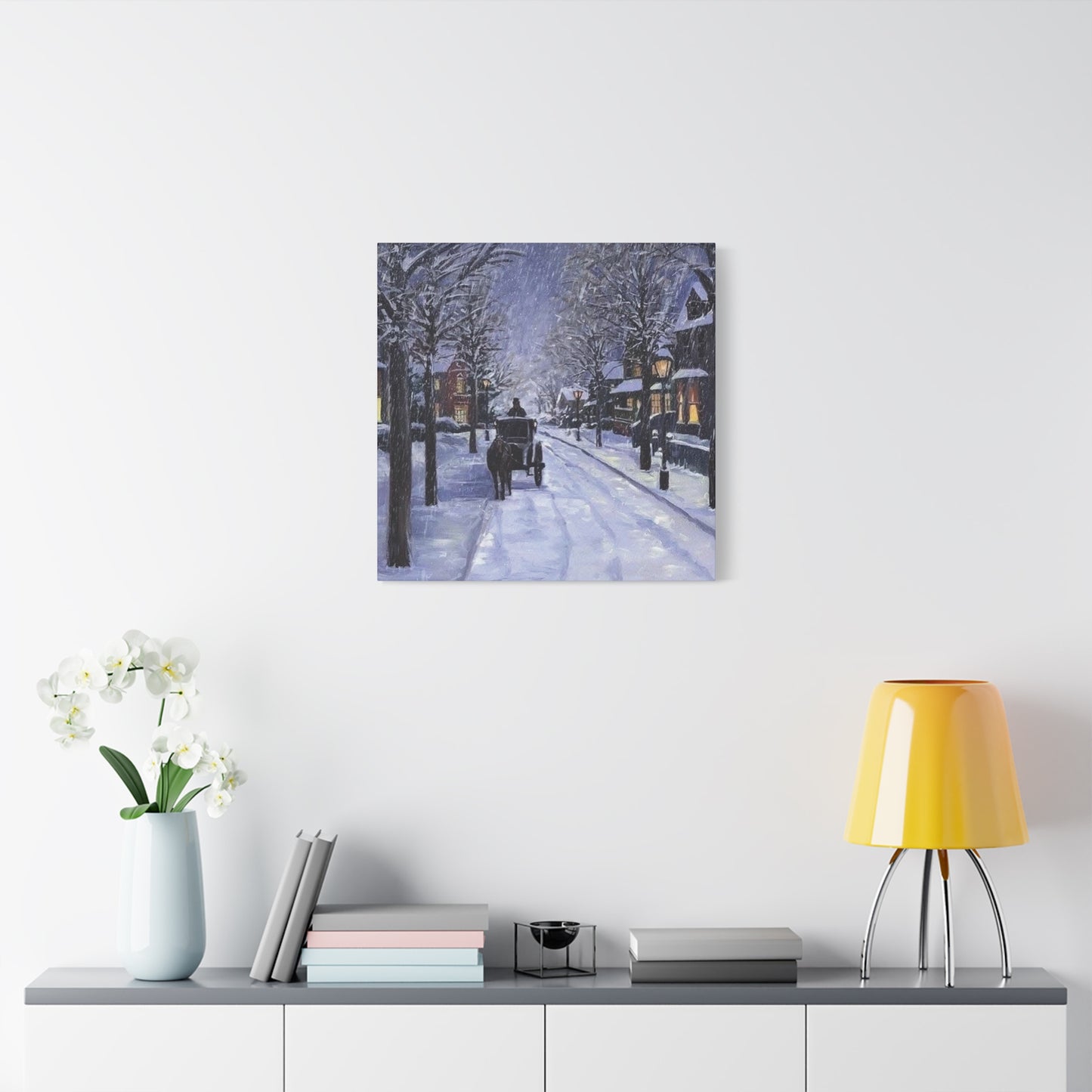 Framed artwork of a snowy street scene on a wall above a shelf with decor items.