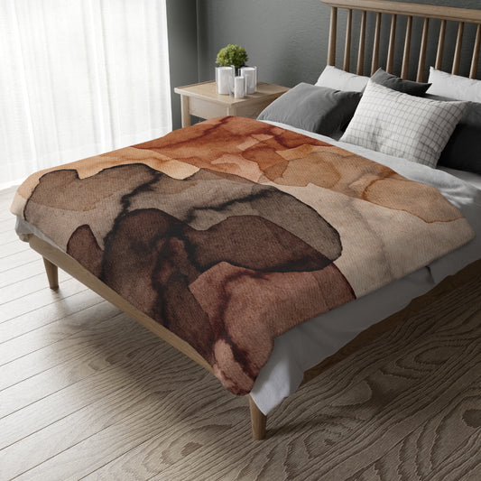 Bed with a patterned brown and beige blanket in a bedroom setting.