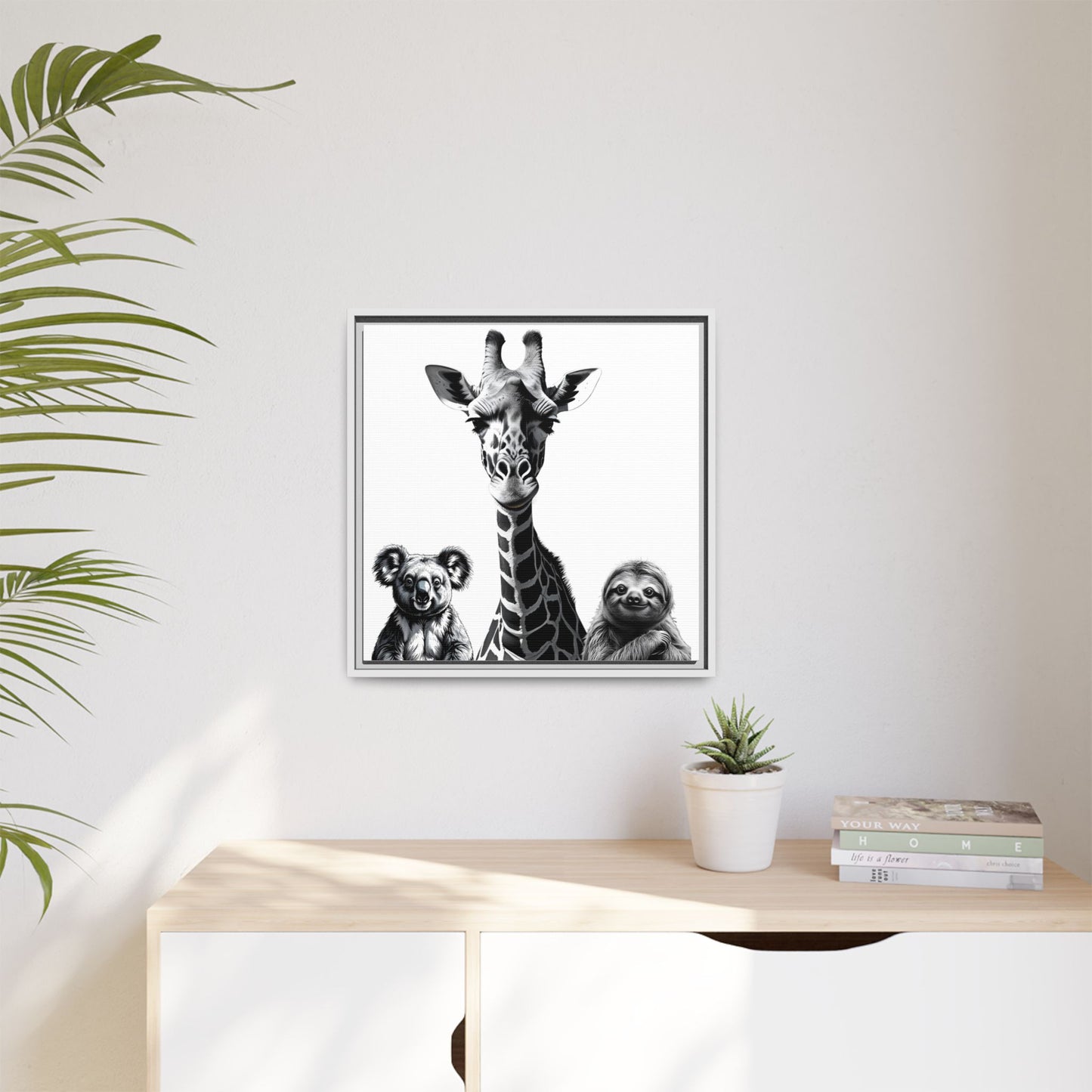 Framed artwork of a giraffe, koala, and sloth on a wall above a desk with plants.