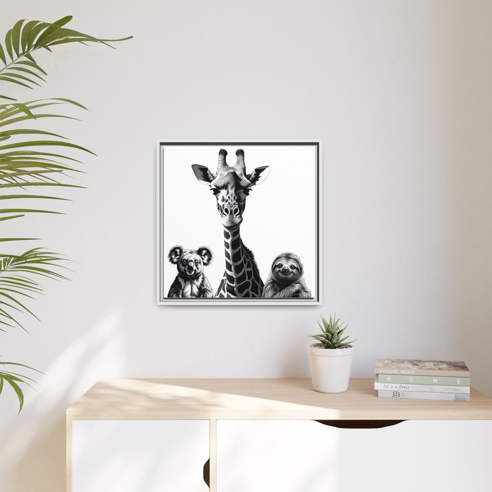 Framed artwork of a giraffe, koala, and sloth on a wall above a desk with plants.