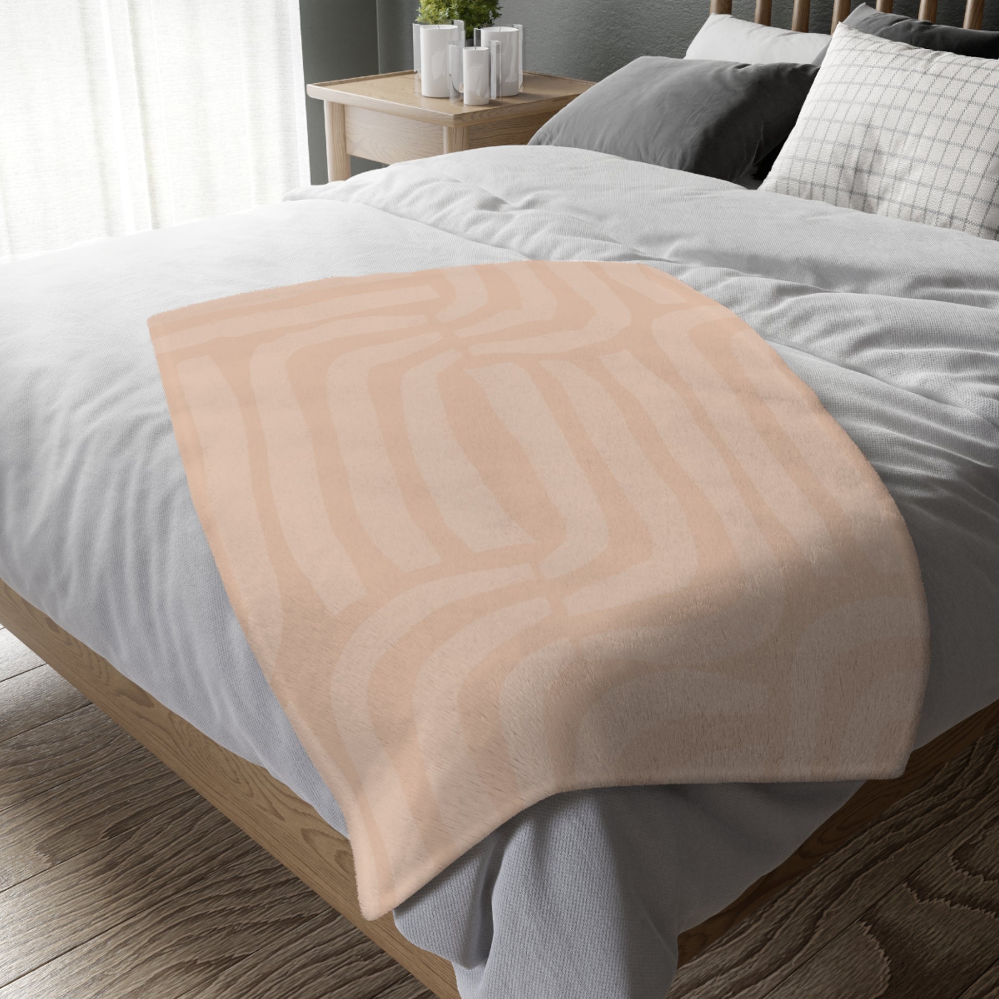 Beige blanket draped over a bed with white bedding and gray pillows.