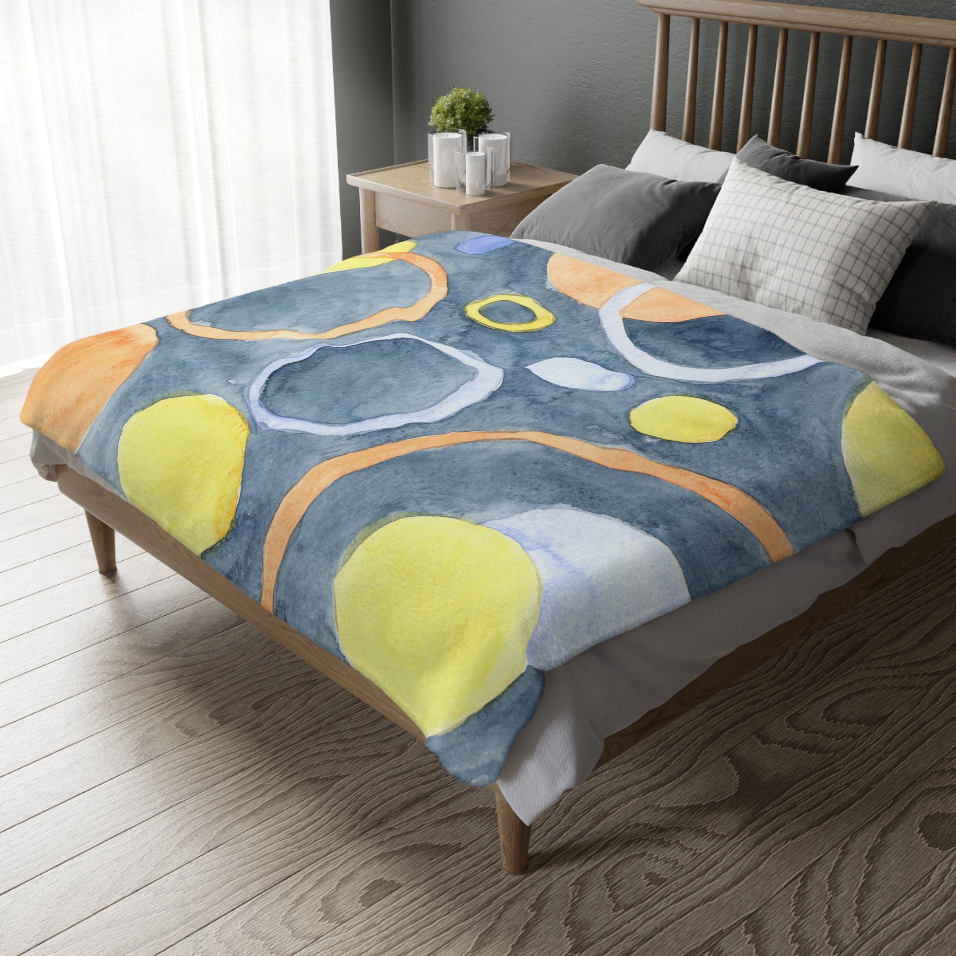 Bed with a colorful abstract patterned blanket in a bedroom setting.