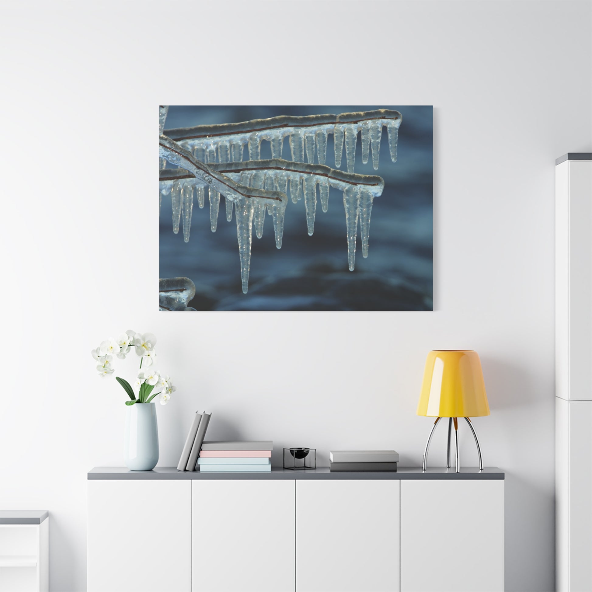 Framed artwork of icicles hanging from a branch above a white cabinet with decorative items.