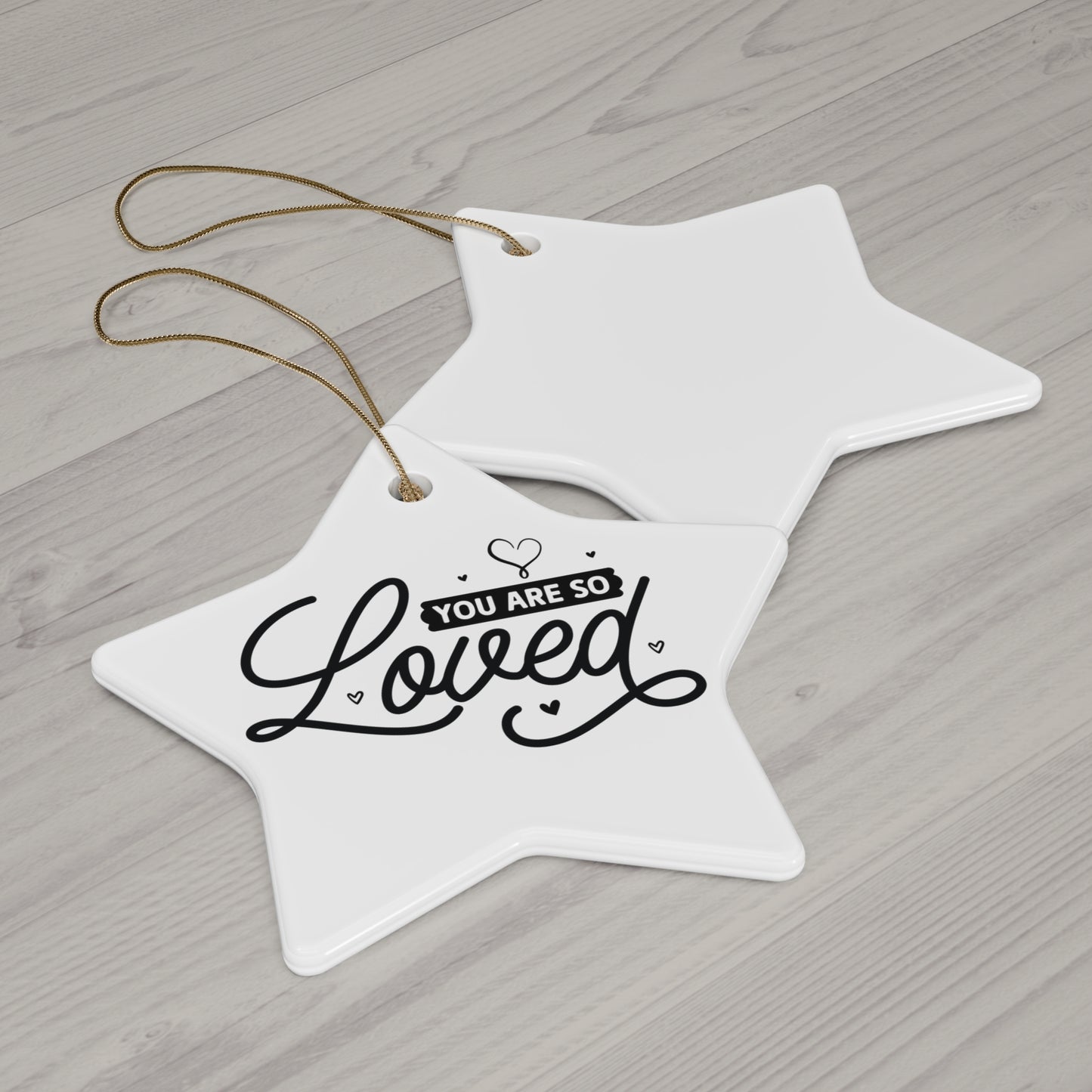 White star-shaped ornament with 'You are so loved' text on a wooden surface