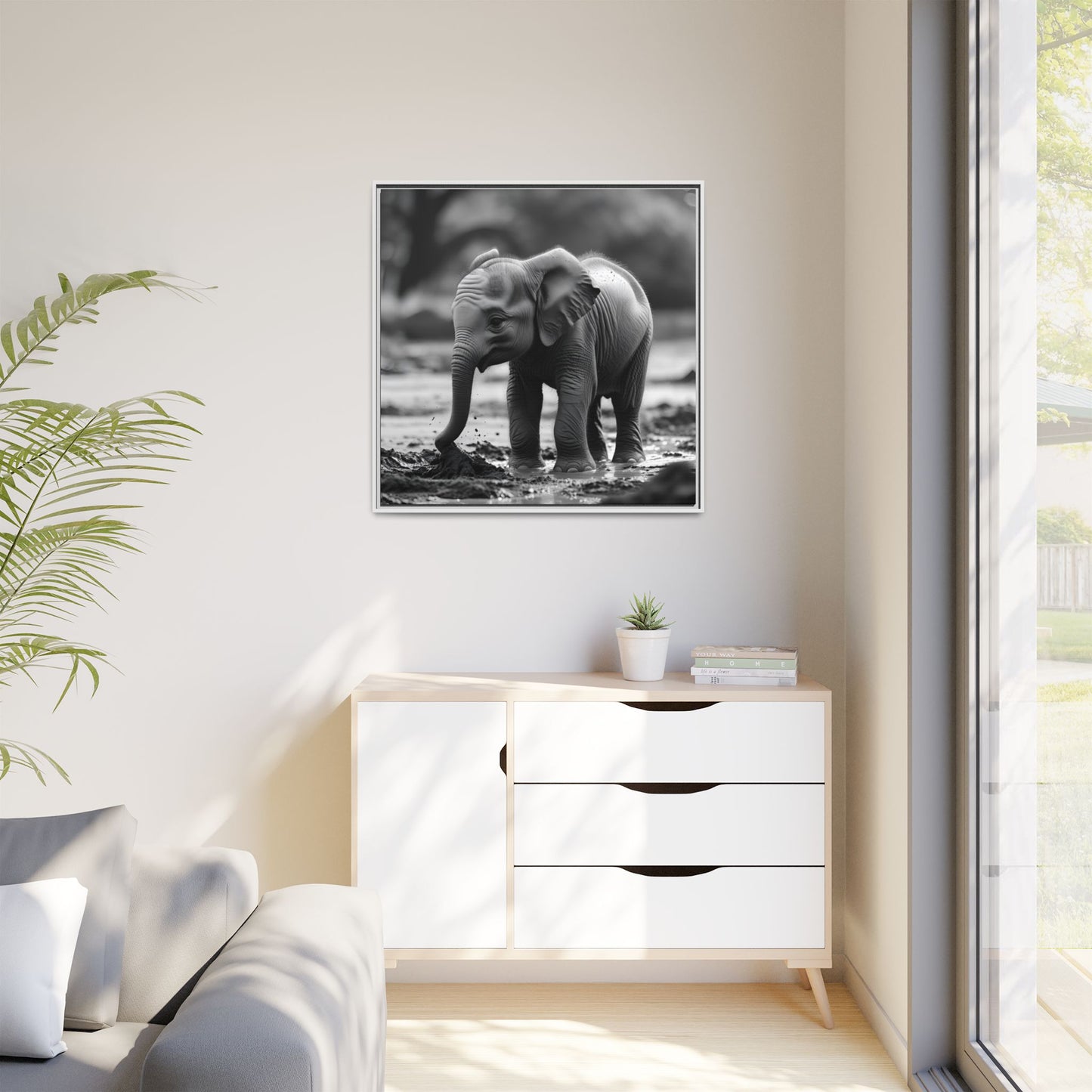 Framed black and white photo of an elephant on a wall above a white dresser.