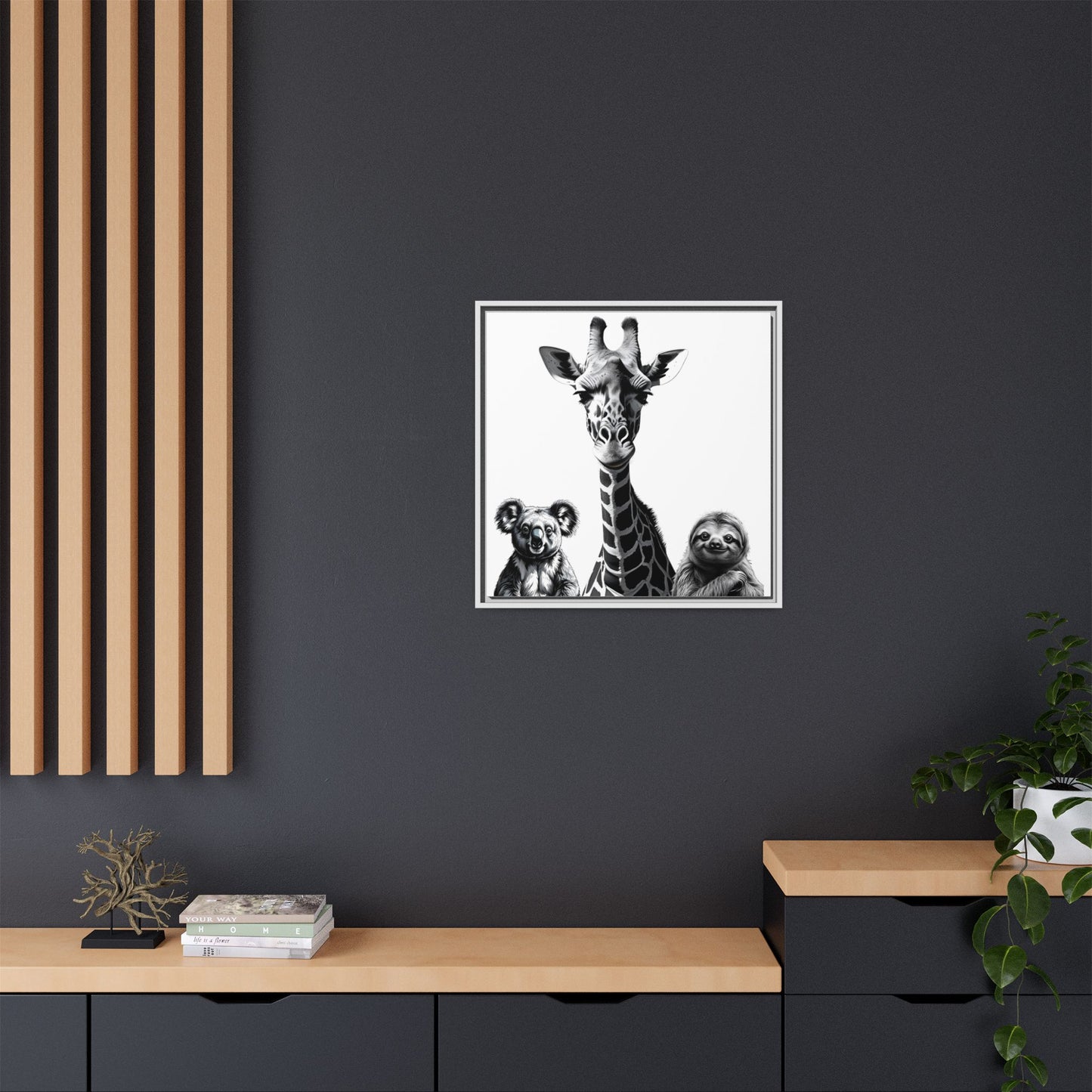 Framed artwork of a giraffe with two sloths on a dark wall above a wooden shelf.