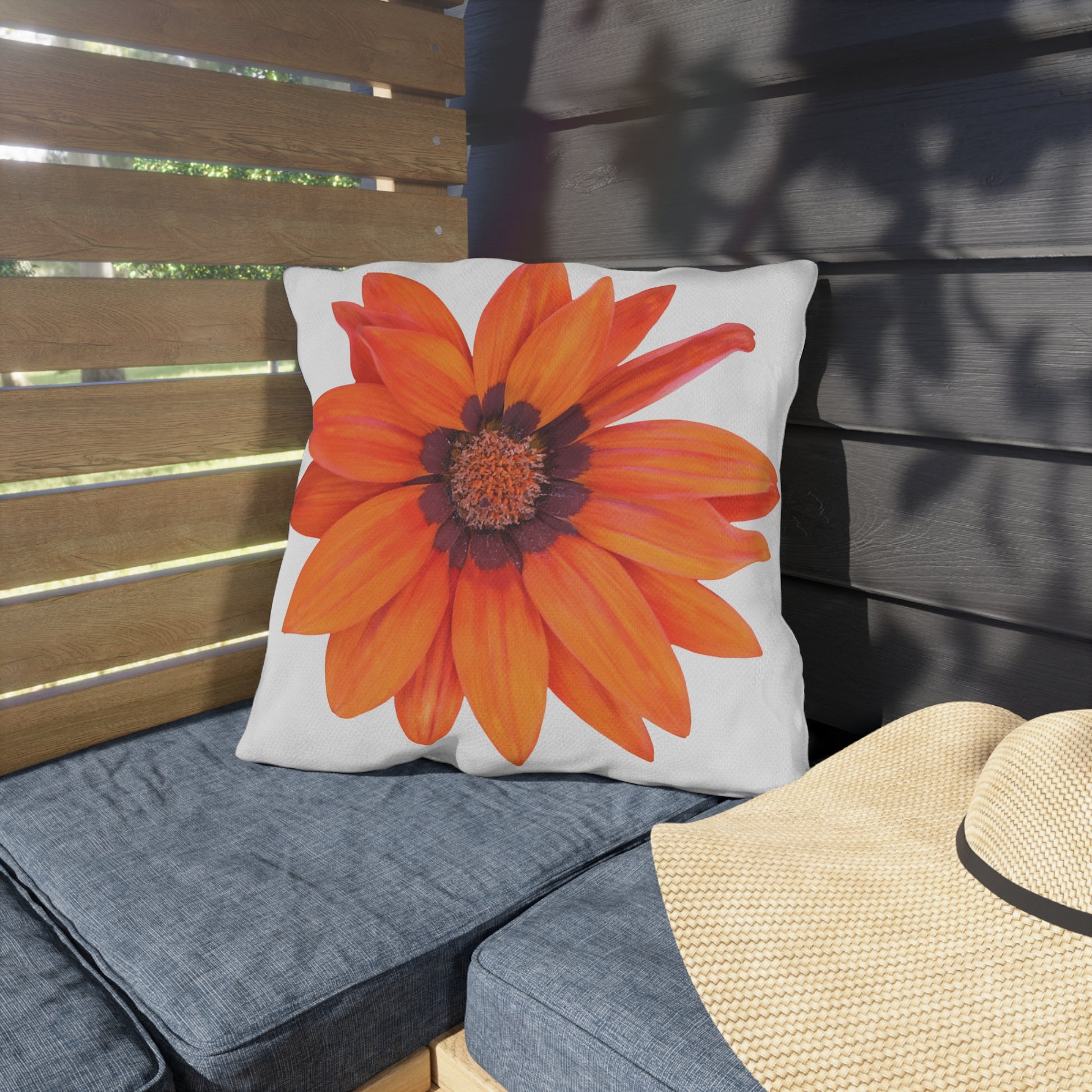 Pillow with a large orange flower design on a wooden bench.