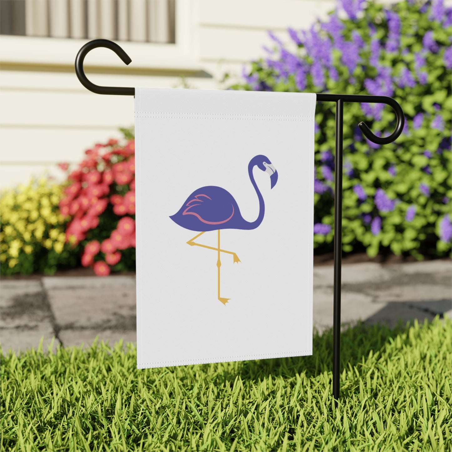 Flamingo-themed garden flag on a stand with flowers in the background