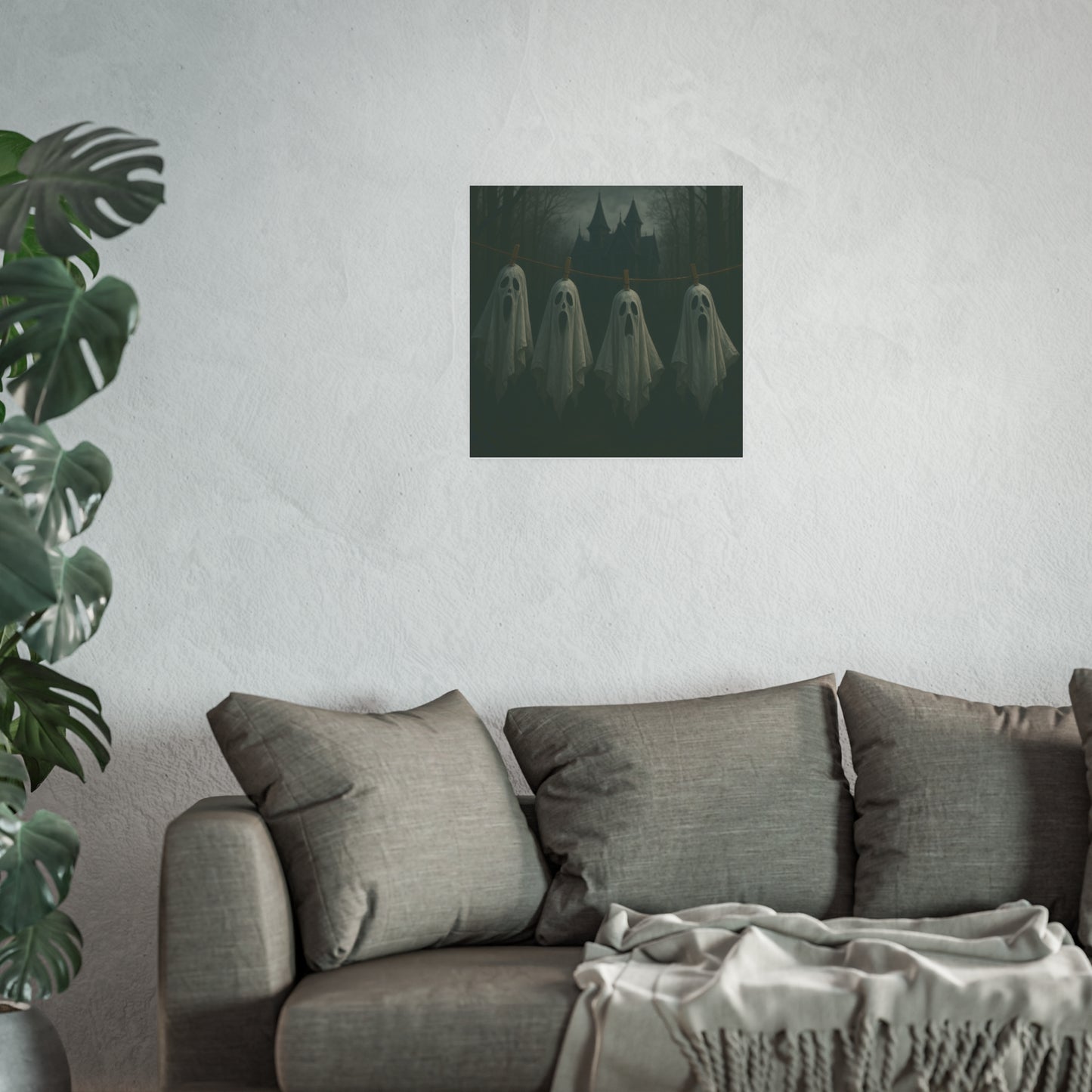 Abstract artwork of a face on a white wall above a gray sofa with a plant to the left.