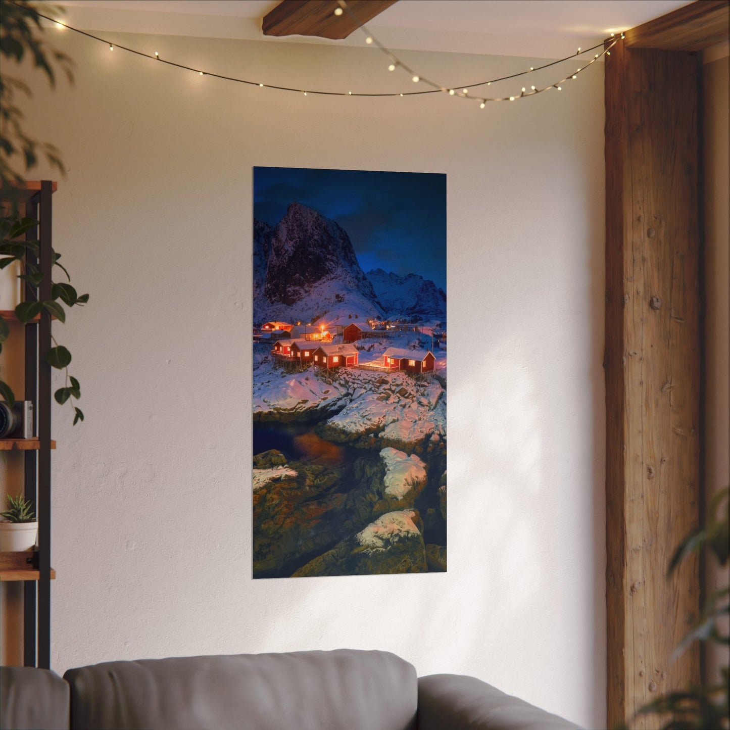 Framed artwork of a mountain village scene hanging on a wall above a sofa.
