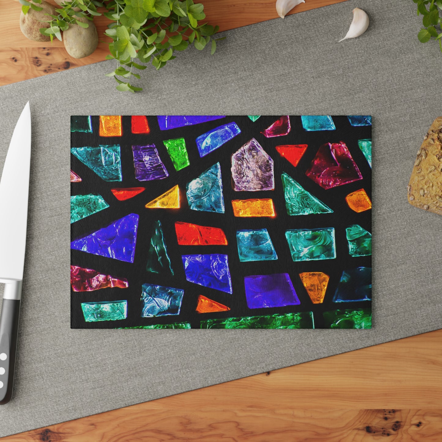 Colorful geometric patterned cutting board on a gray surface with a knife and plant.