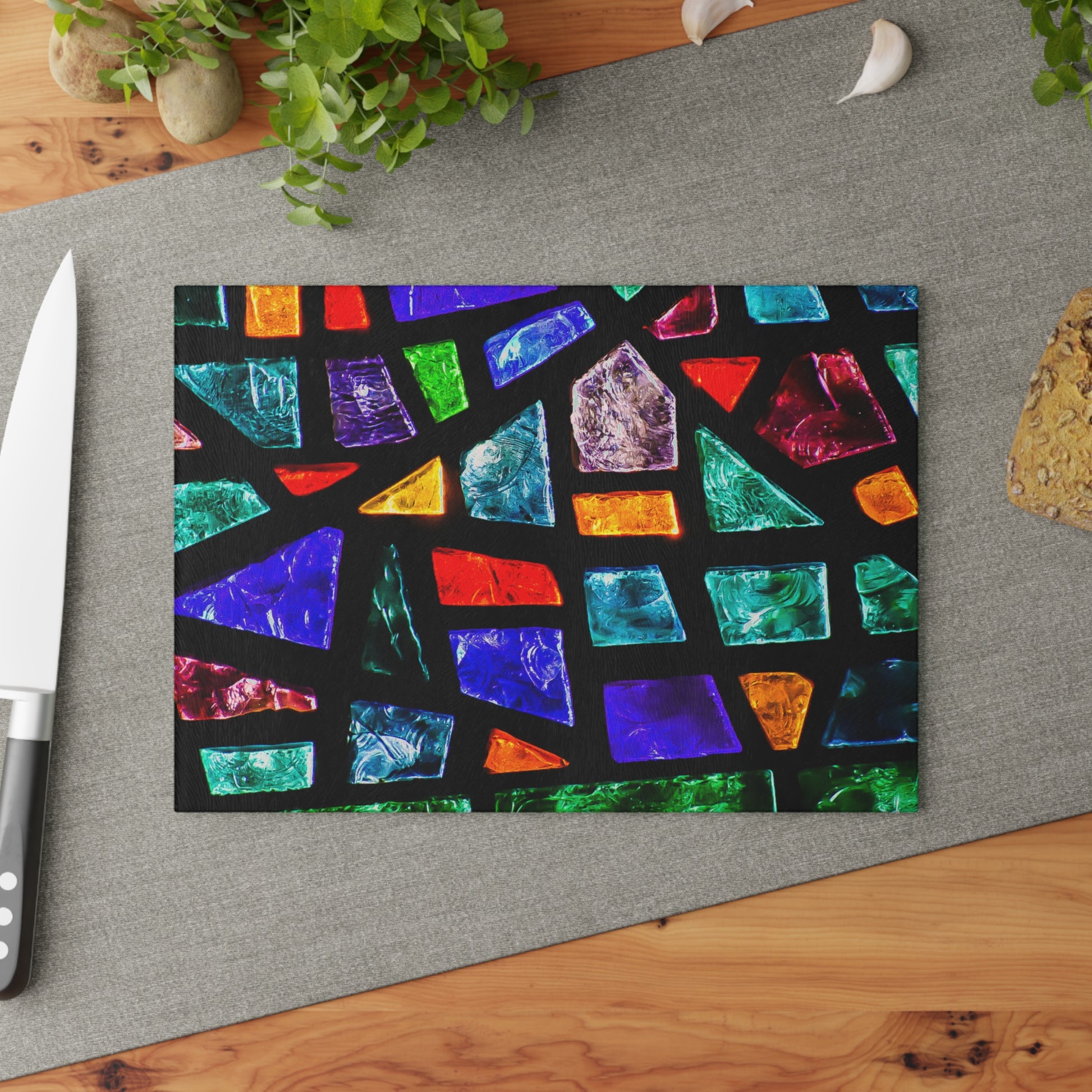 Colorful geometric patterned cutting board on a gray surface with a knife and plant.