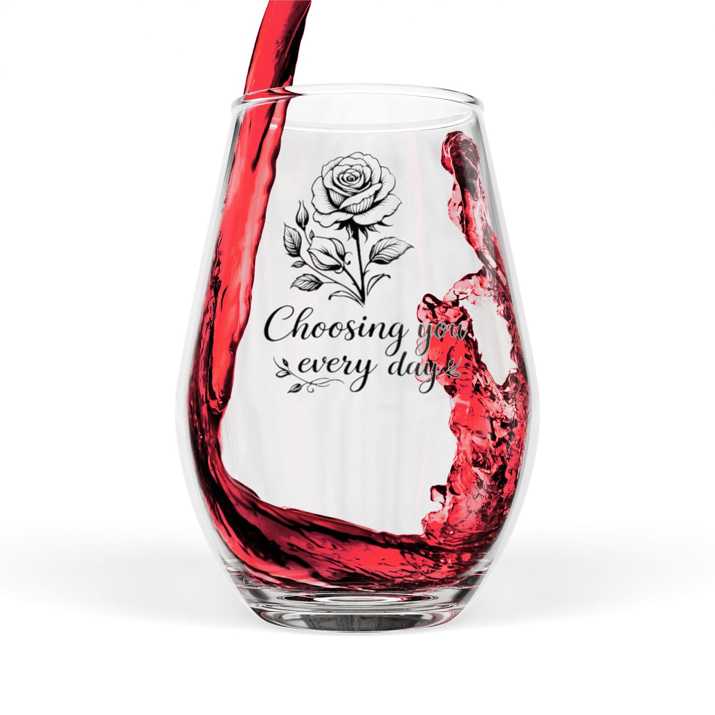 Clear wine glass with red wine being poured, featuring a rose design and text.