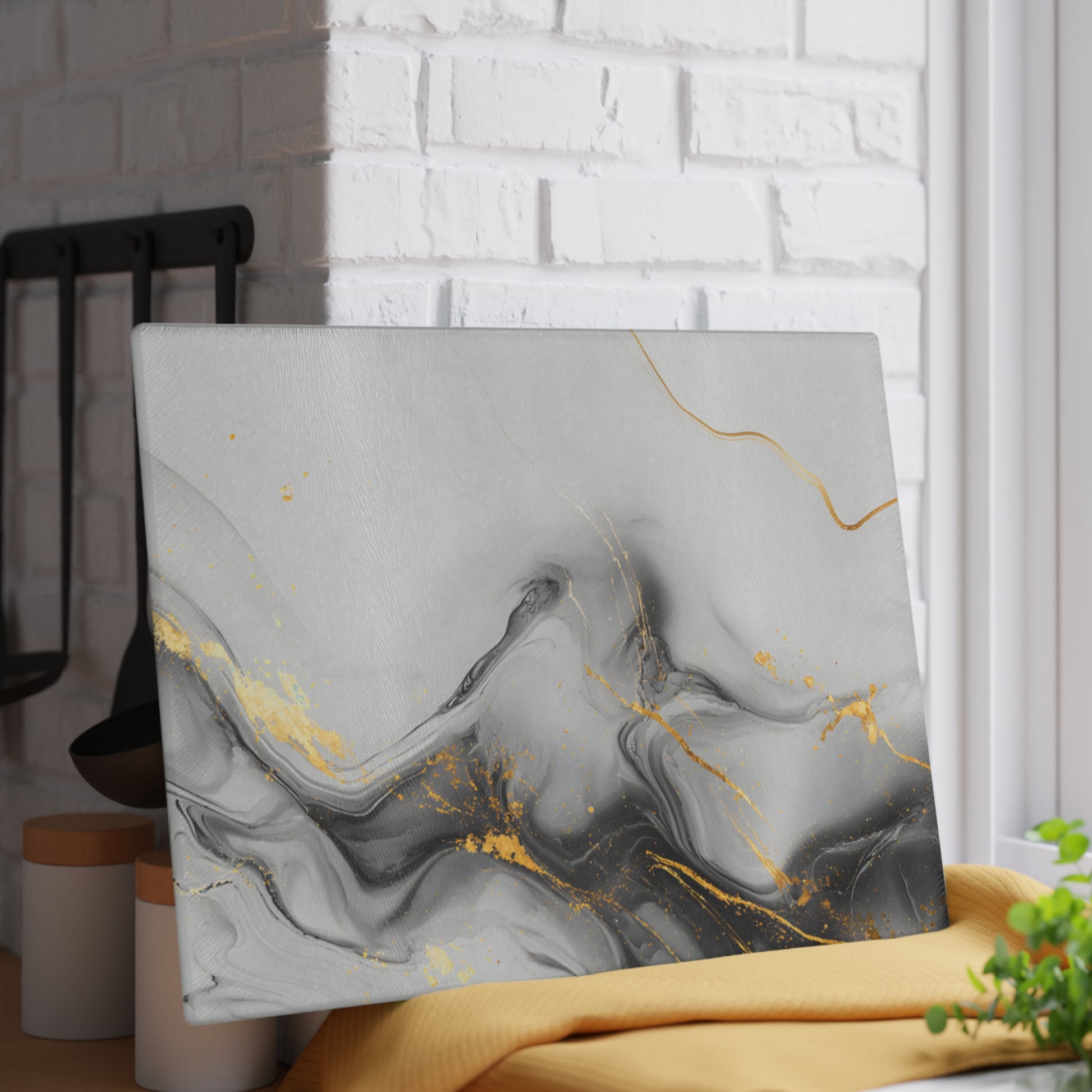 Abstract art piece with gold and gray marbling on a white brick wall background