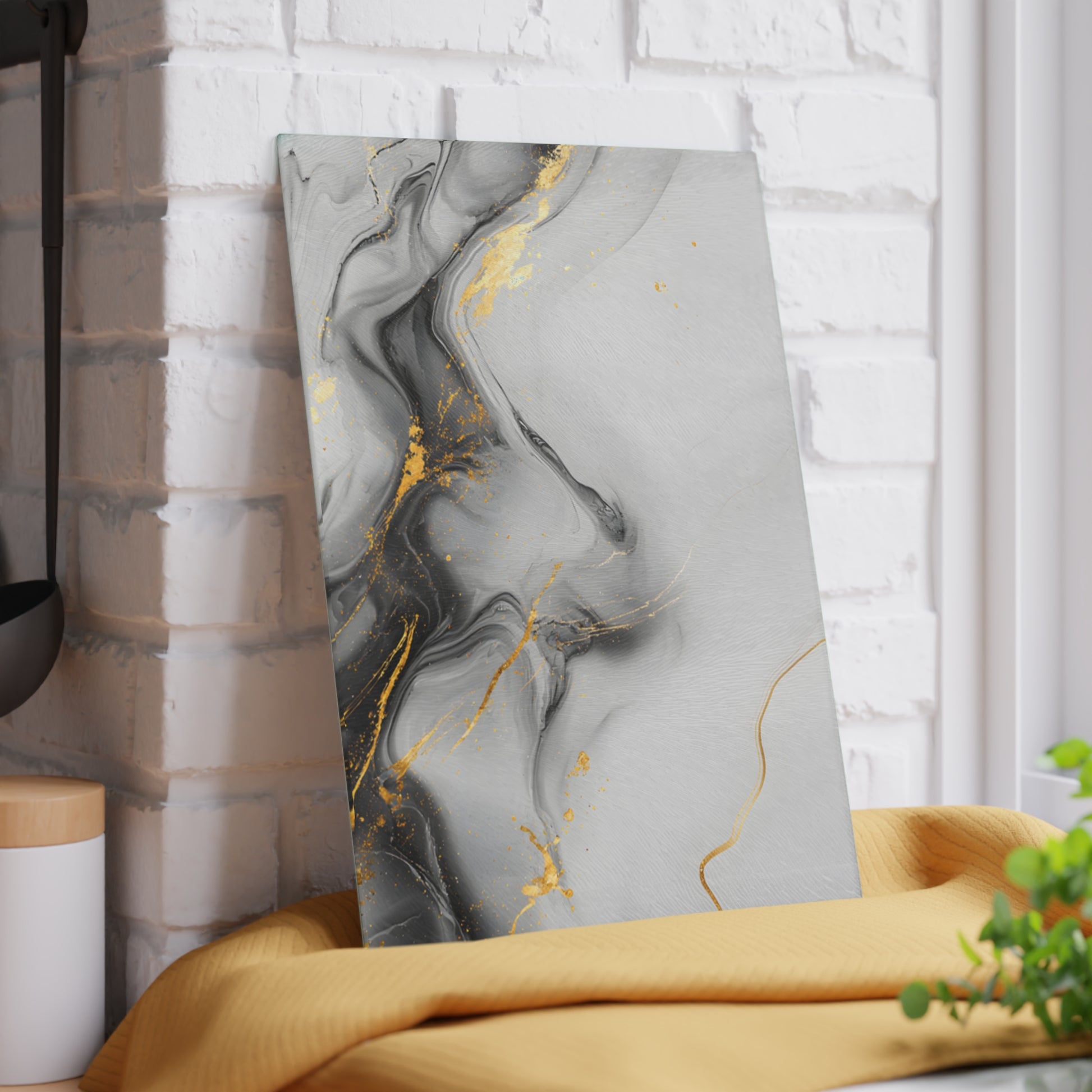 Abstract art piece with gold and gray design leaning against a white brick wall.